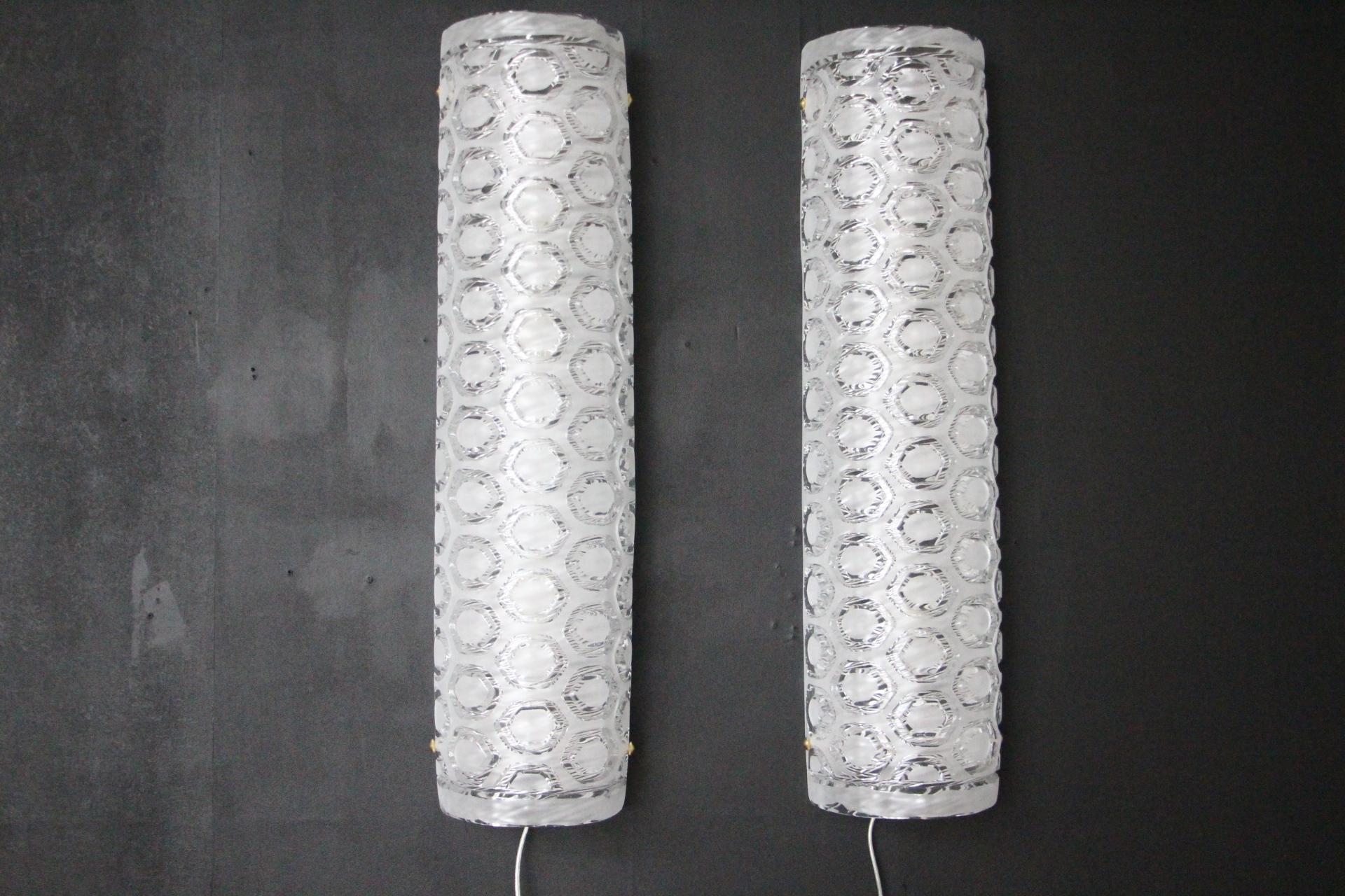 This pair of hand crafted wall lights features thick textured ice Murano glass cylinder shape with a geometric stamped pattern. It creates a unique and beautiful movement reminiscent of modern decors or Haute Couture, in the style of Pierre Cardin