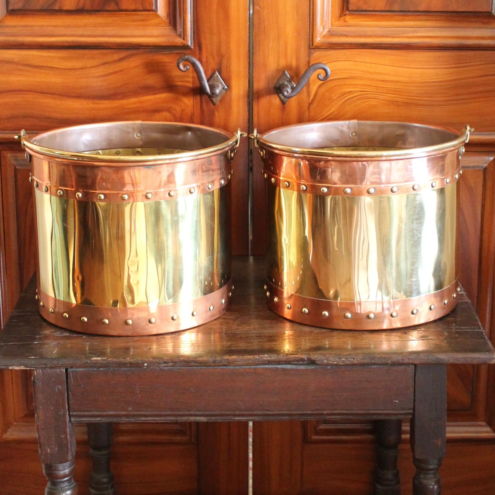 A pair of substantial brass fireplace buckets banded top and bottom with copper, and attractively studded with brass rivets along the seams. A great English look, suitable for holding kindling, for a fancy wastebasket or for decorative use.