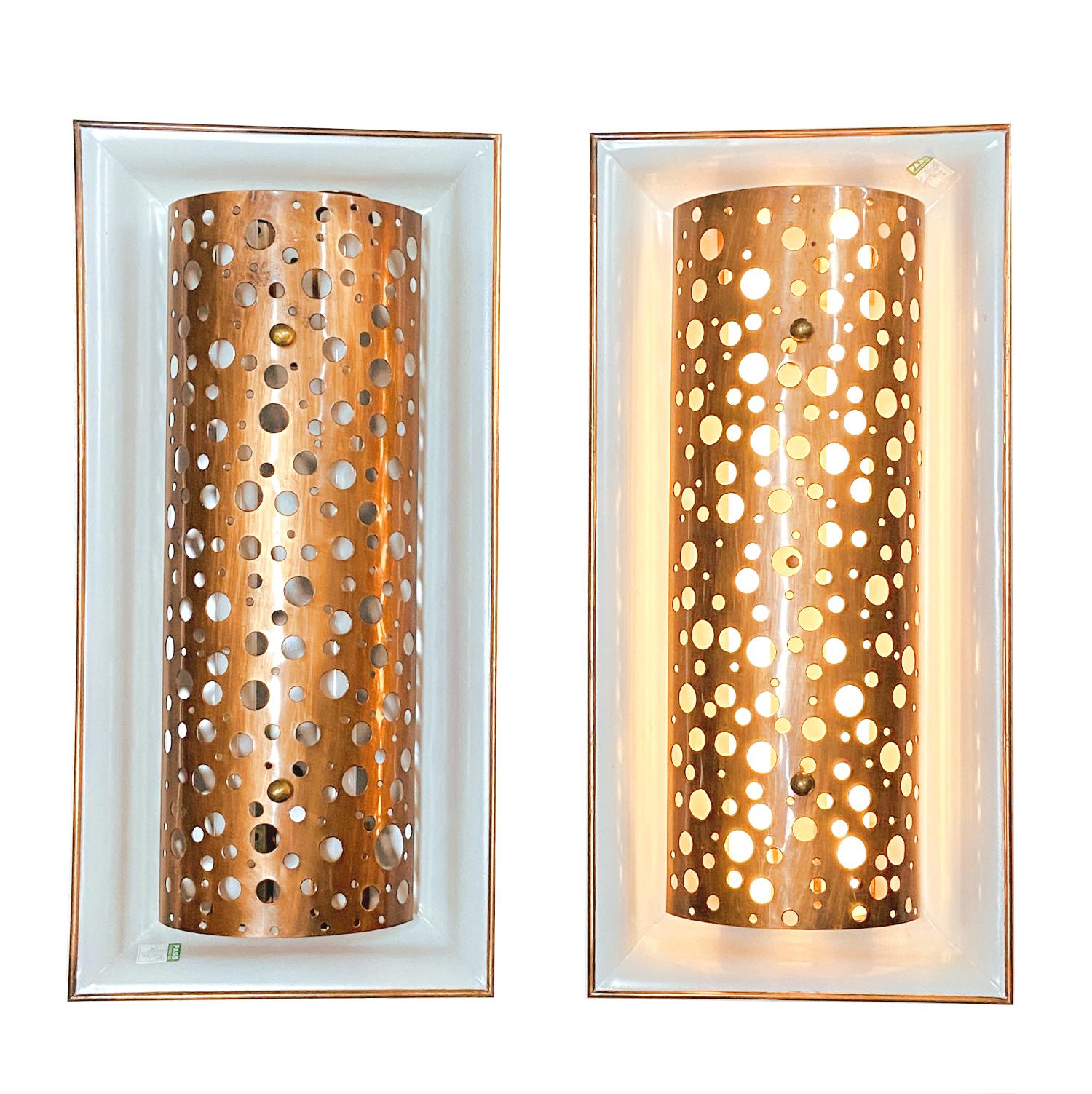 Gran par de apliques metálicos de los años 50 hechos a medida con difusores curvos de cobre decorados con perforaciones aleatorias de gran tamaño que crean un cielo nocturno lleno de estrellas. Las placas traseras rectangulares de metal gris claro