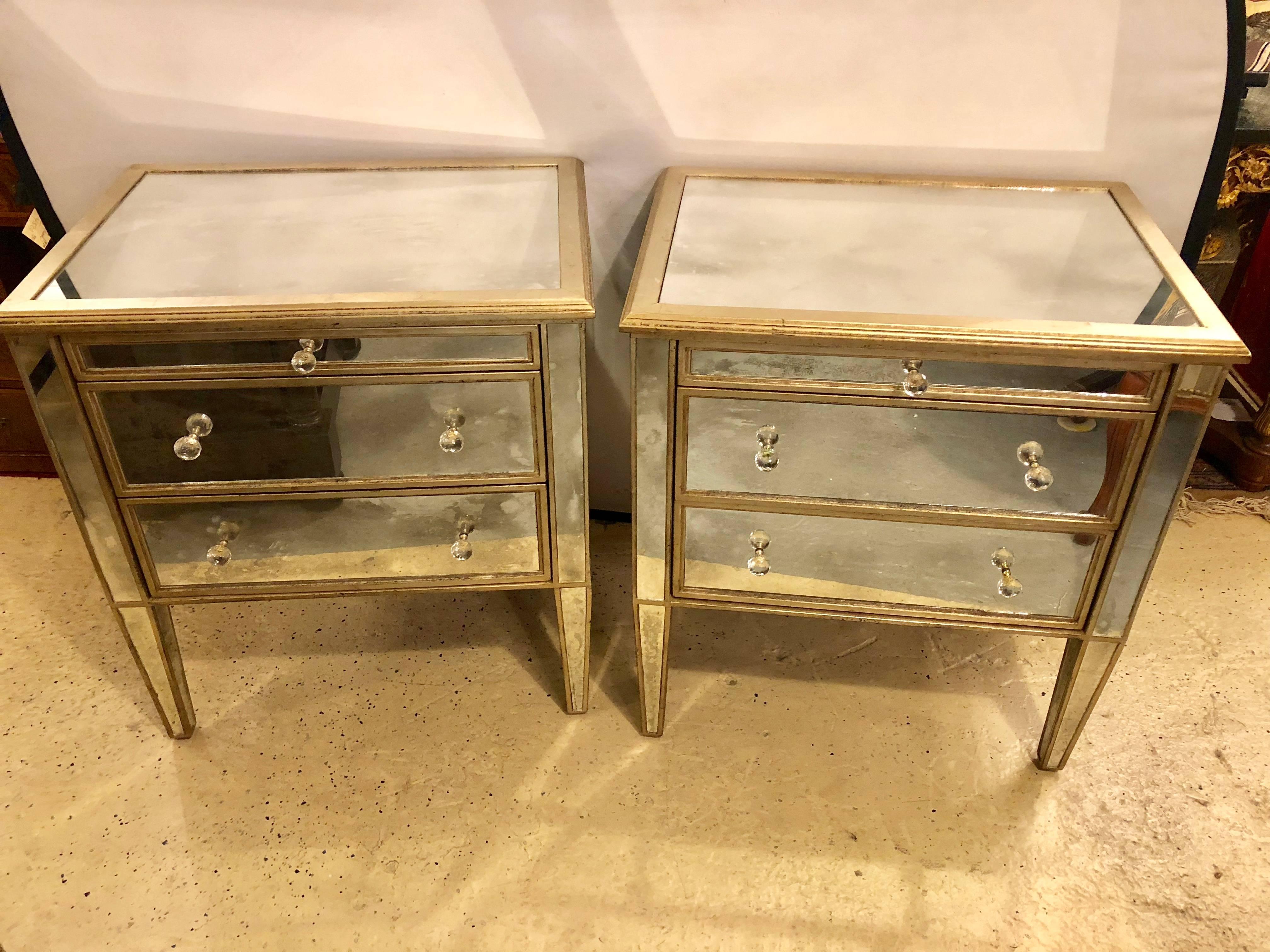 Pair of Hollywood Regency style custom three-drawer antiqued mirror nightstands or commodes. Mirrored on all sides including the back on these fine custom quality mirrored commodes or night stands. Each having two drawers under a pull-out serving or