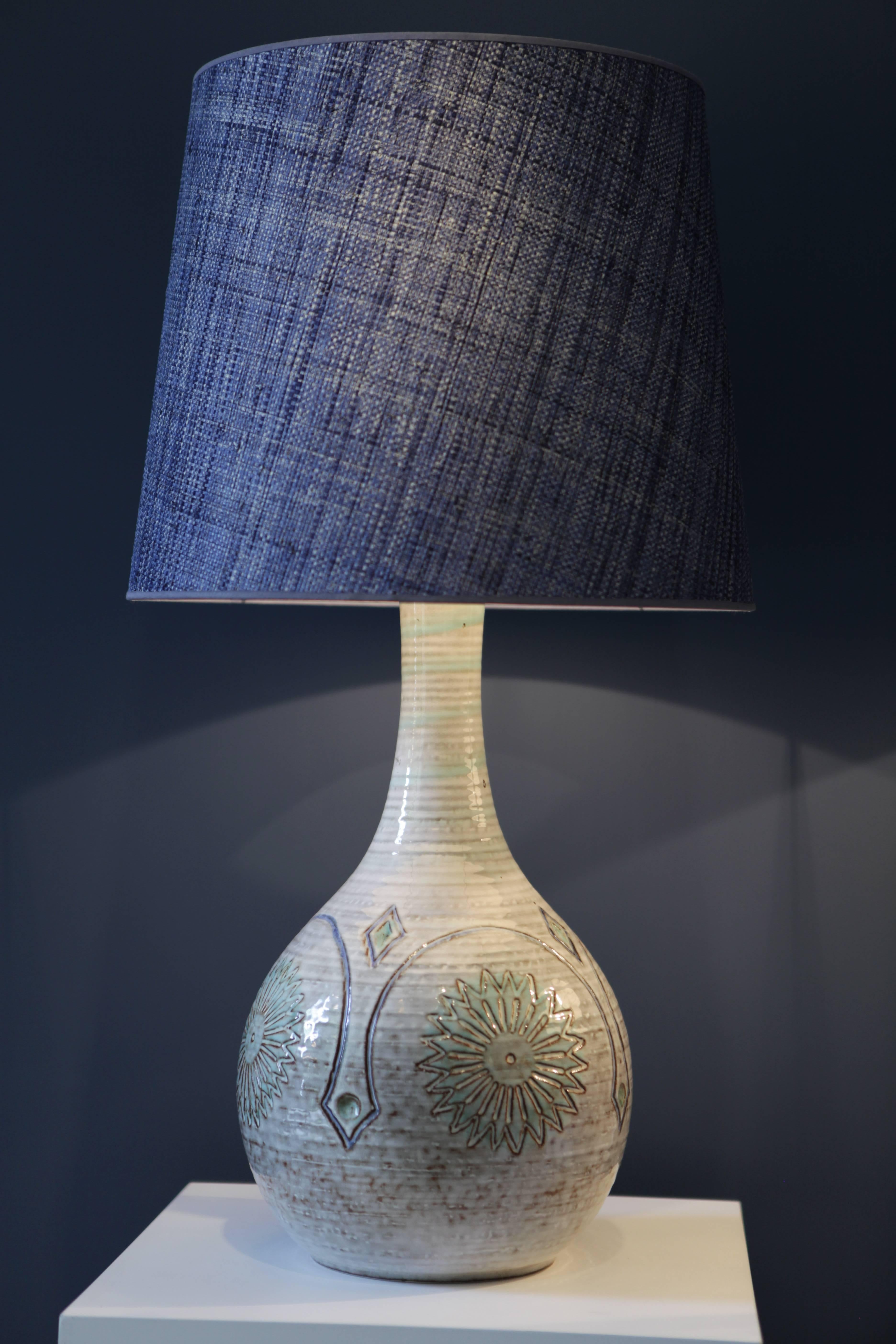 A pair of large and beautiful stoneware table-lamps
Signed to the underside 'Bornholms Stentøj Søholm Denmark'
Midcentury relief design in soft blues and greens on a light pastel colored ground, glazed
Special handmade denim blue raffia shades,