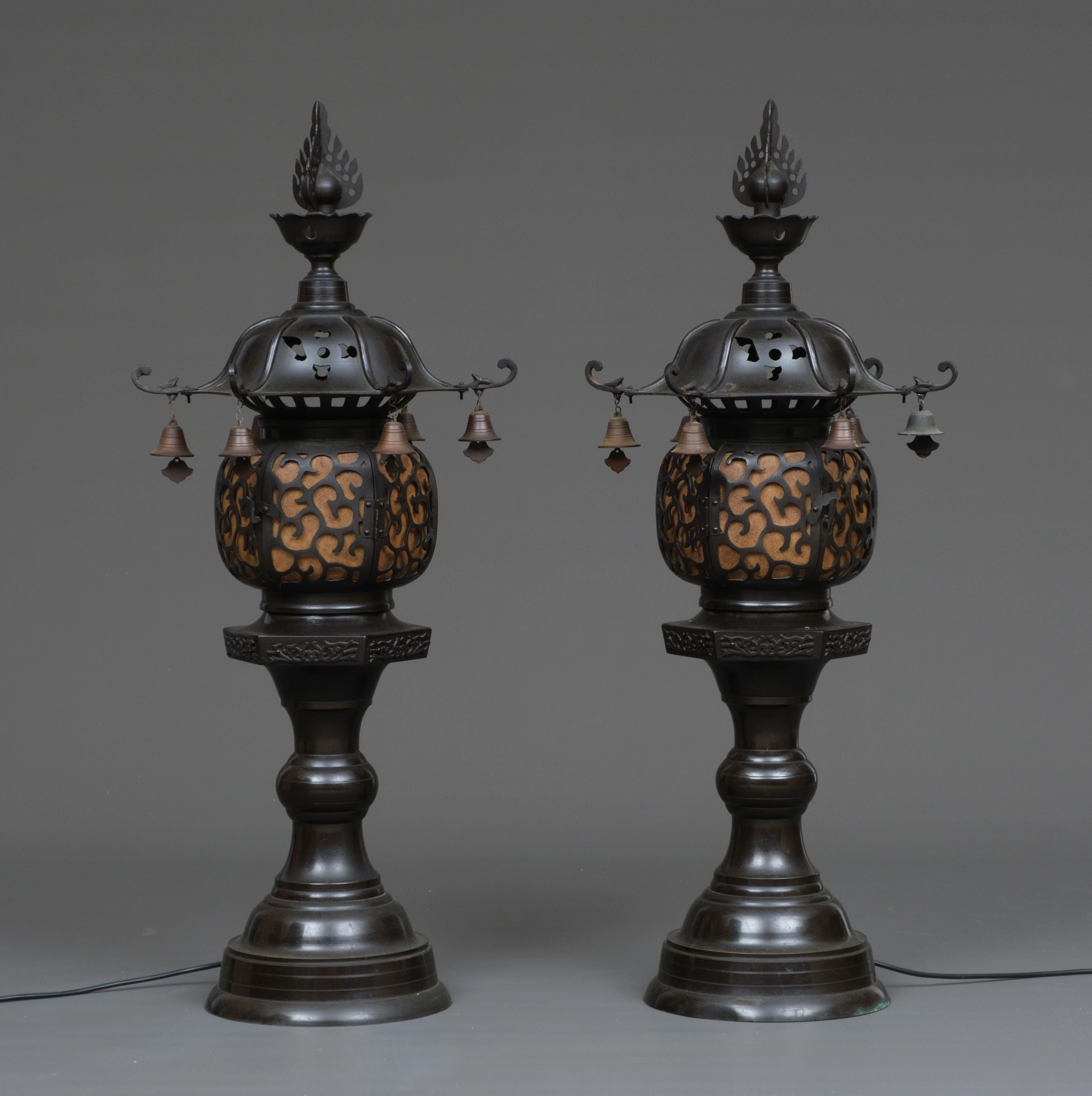 A pair of amazing, large dark brown patinated bronze Japanese electrified lanterns (tôrô). The pagoda-shaped top crowned by a hôju (sacred jewel) and fitted with ‘warabite’-shaped points hung with bells. The body with an openwork scrolling vine