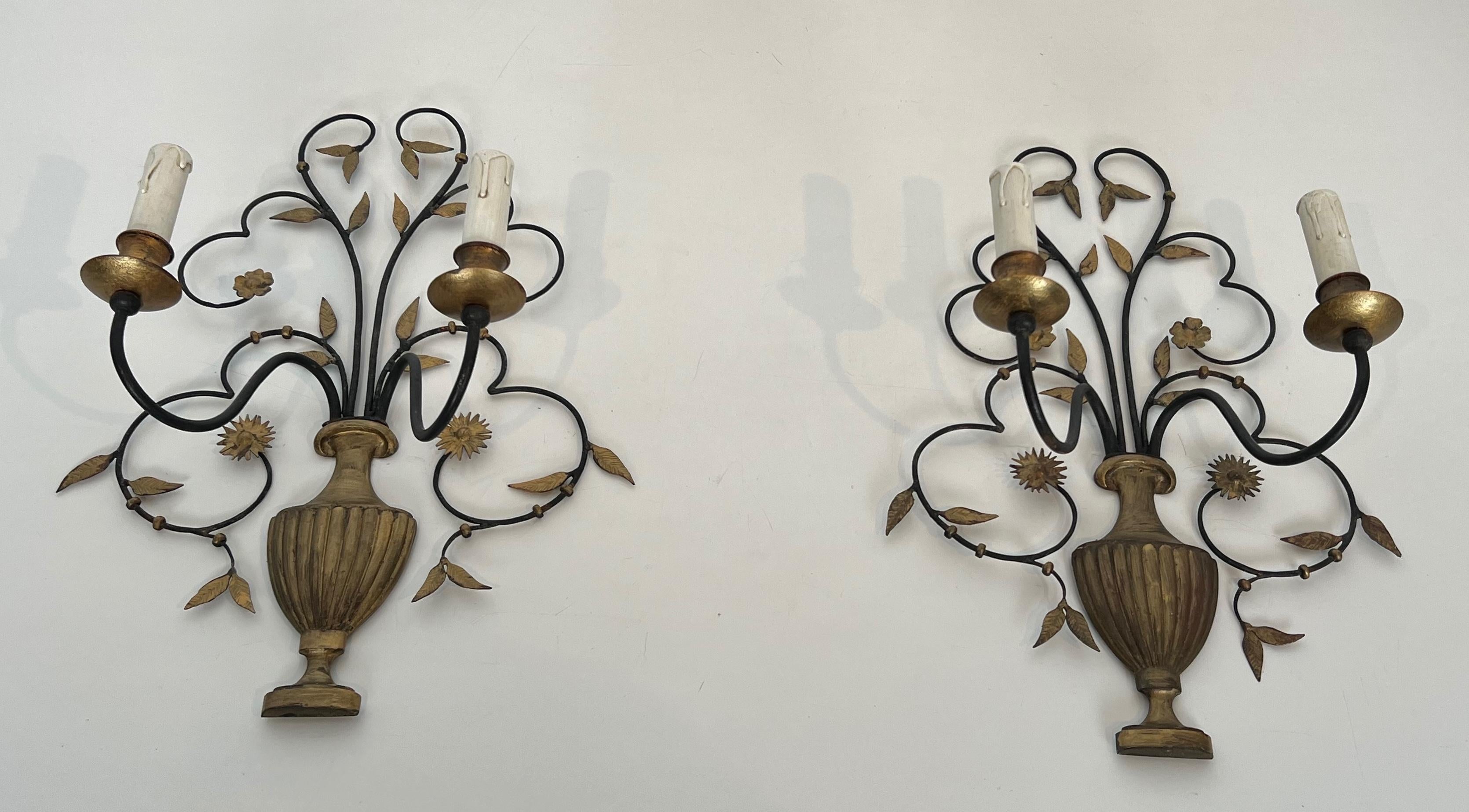 This beautiful and large pair of decorative wall lights is made of  wrought and gilded iron. These wall sconces represent a bouquet of flowers. This is a French work. Circa 1940