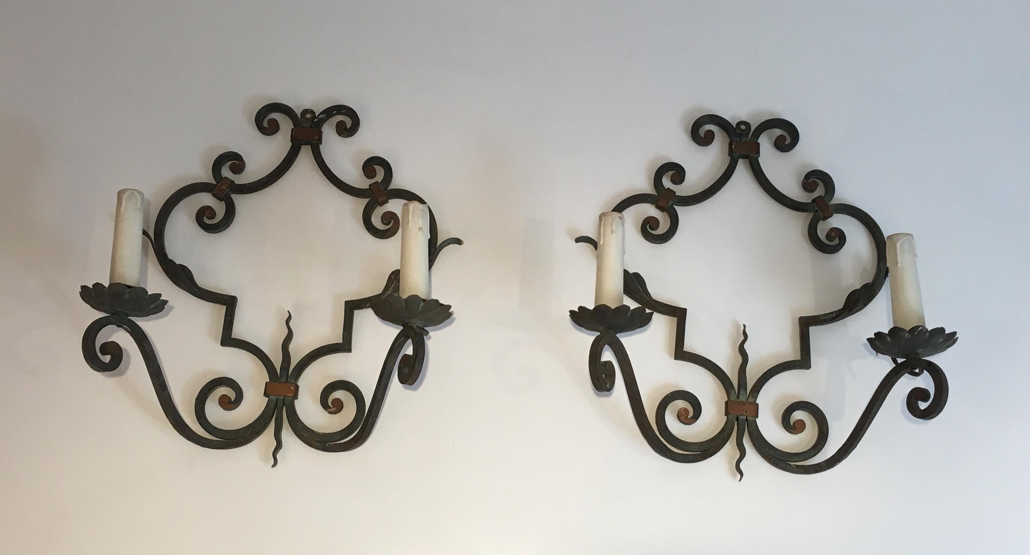 Questa grande e decorativa coppia di applique è realizzata in ferro battuto. Si tratta di un'opera francese del 1950 circa.