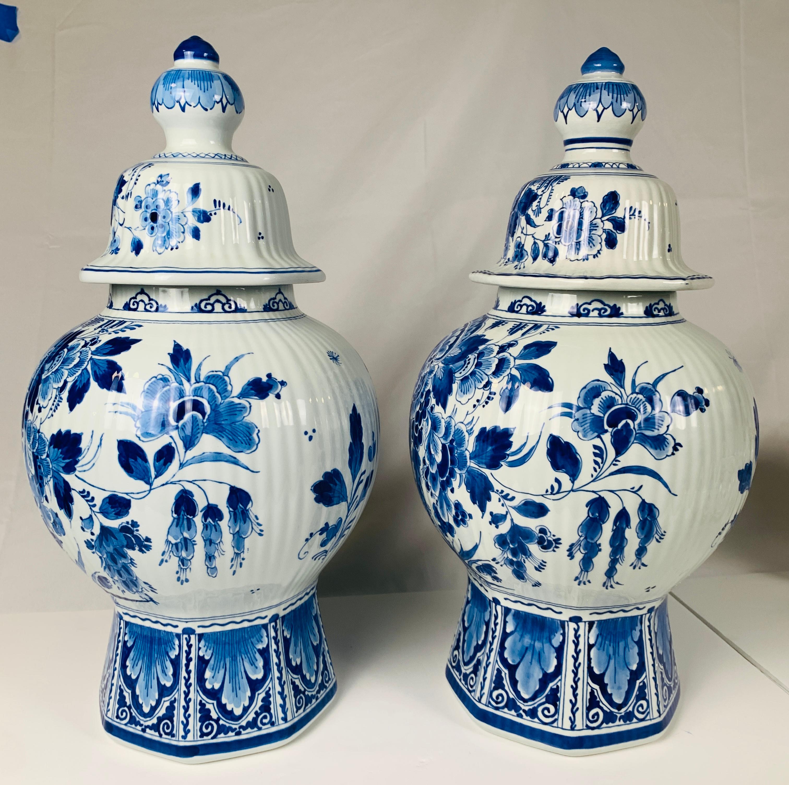 Painted in fabulous deep cobalt blue, this pair of Dutch Delft blue and white jars feature a pair of beautiful quails under a wild profusion of flowers. 
The decoration is exquisite. 
The ribbed body rises from a traditional octagonal base decorated