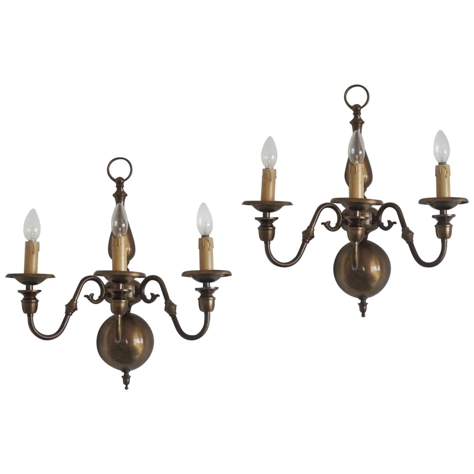 Pair of Dutch or Flemish hand cast brass wall sconces from the 1930s with three arms in double volute, long nozzles and bulbous bases. Classic
Flemish styling with a baluster or ball shape at the base and long sweeping arms. The brass is solid with