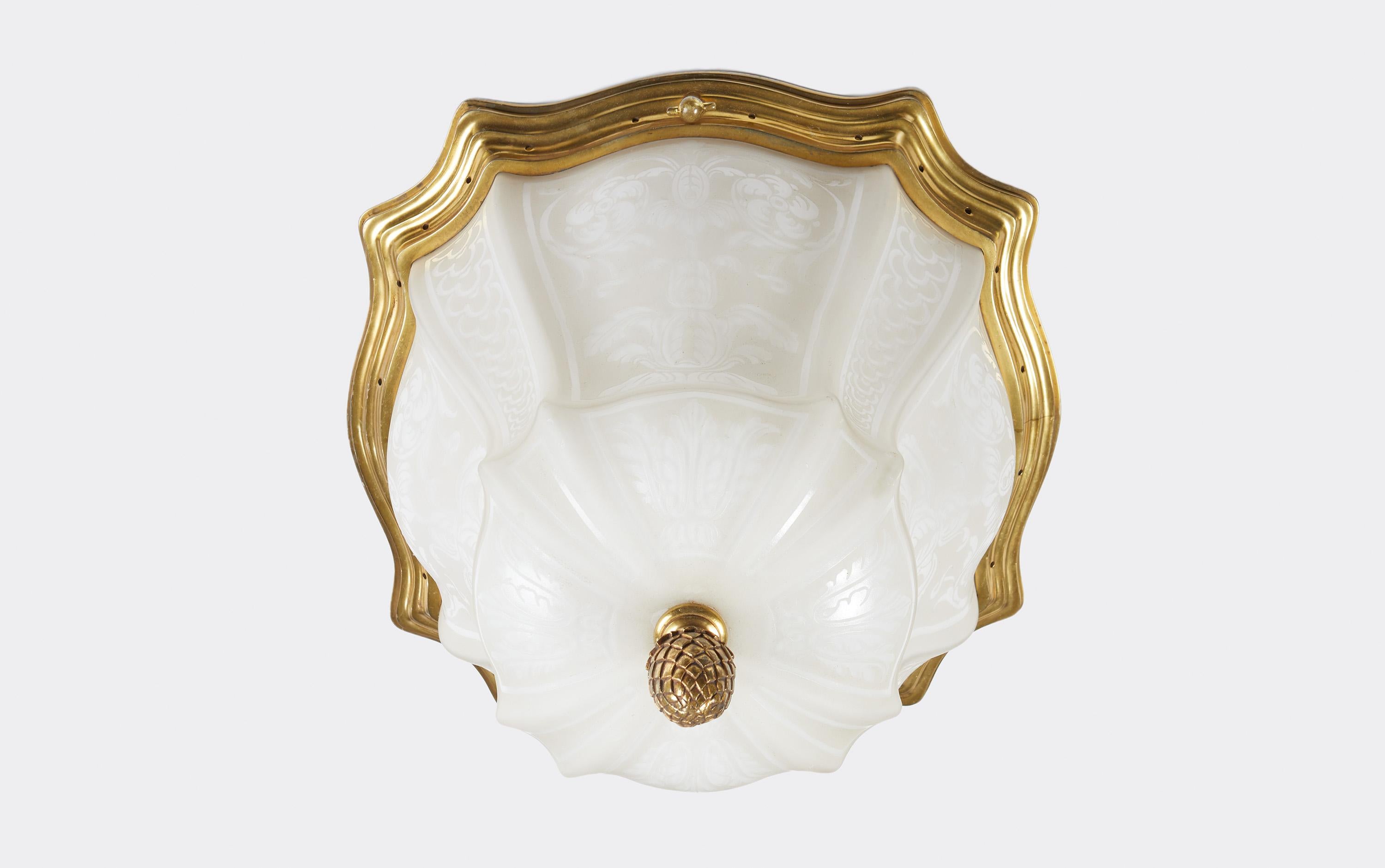 A pair of signed Caldwell flushmounted fixtures, circa 1920. The shaped cameo-style glass dome with classical motifs. With shaped gilt bronze frame and with acorn shaped finials on the underside. Signed by American maker Caldwell. A beautiful pair