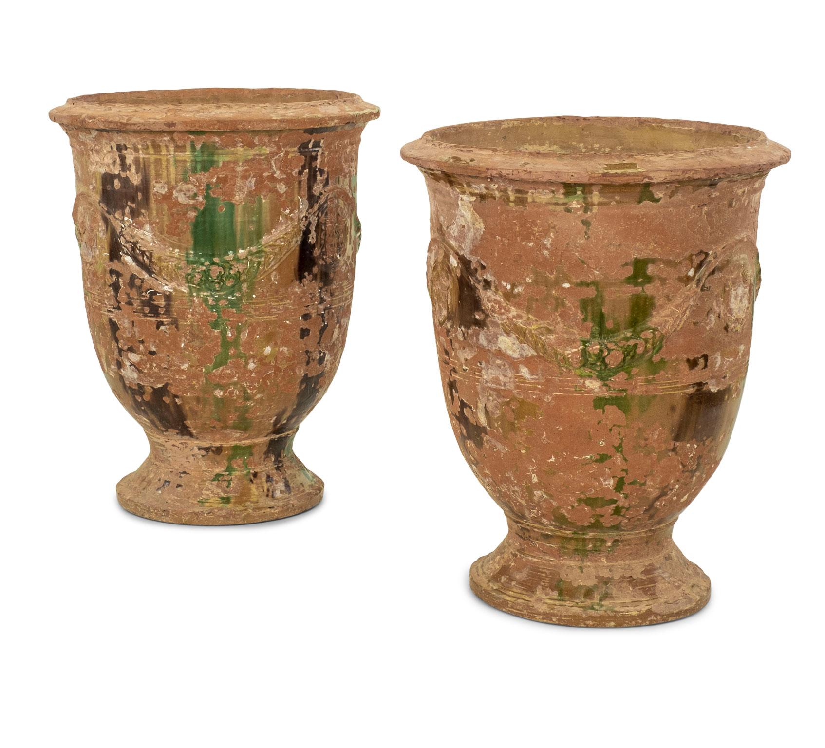 Pair of large mid-19th century Anduze jars. Decorated in dark brown and green drip glaze and adorned with swag decoration in raised relief. The Boisset mark featured in cartouches. Some minor chipping at bases and rims consistent with age and use.