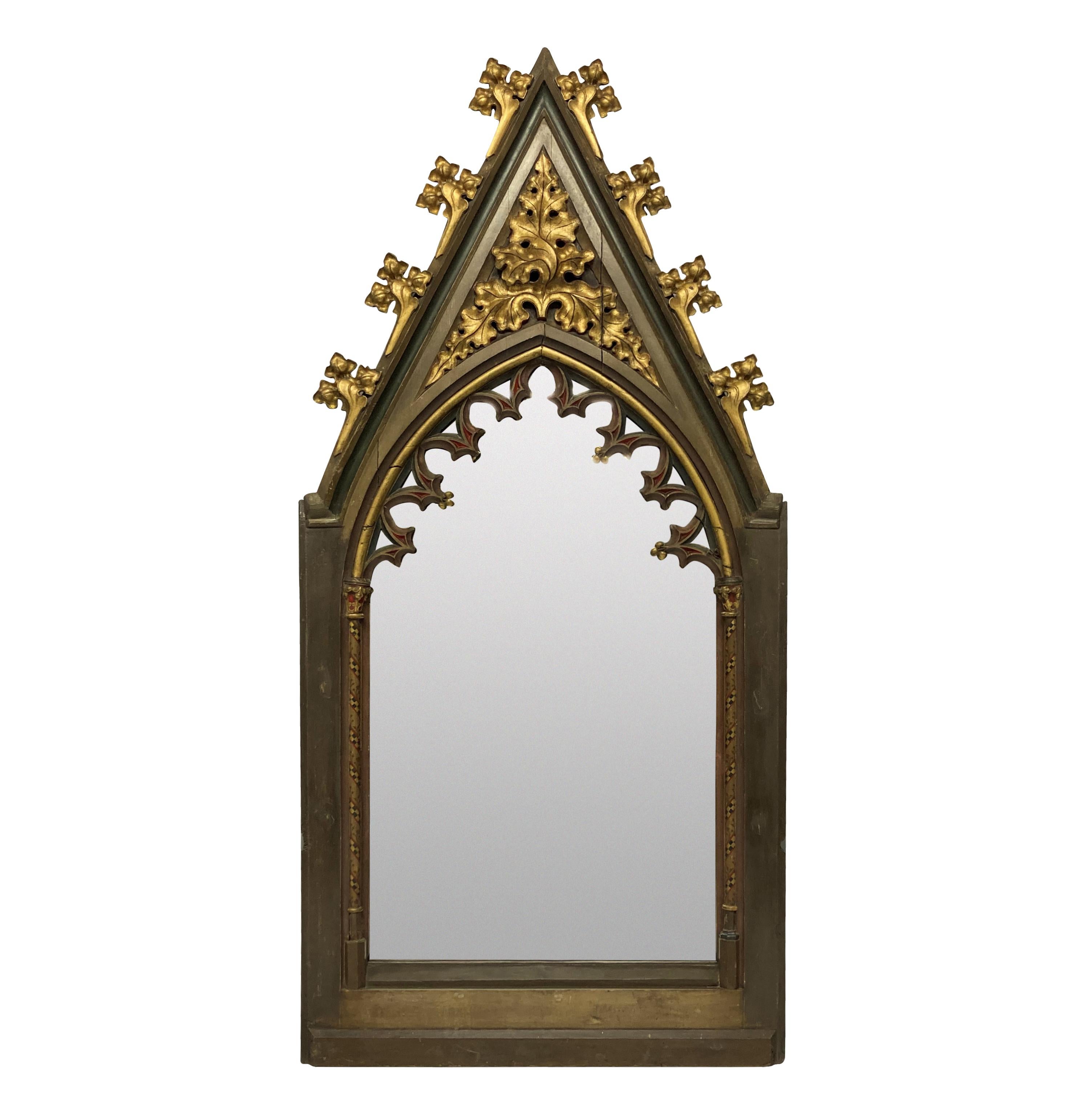 A pair of large English Gothic revival mirrors in polychrome painted and parcel gilded oak. Formerly part of an internal screen or blind arcading, school of Augustus Pugin. The paints are the original.