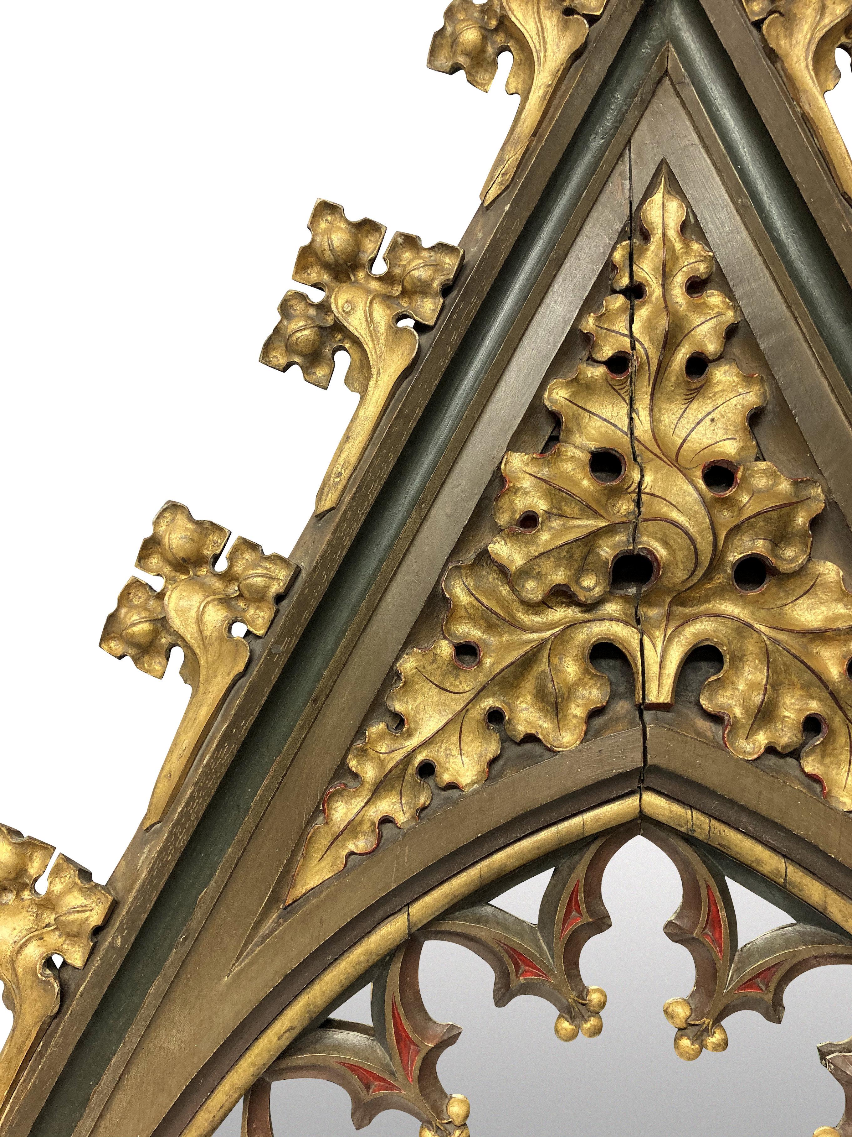 A pair of large English Gothic revival mirrors in polychrome painted and parcel gilded oak. Formerly part of an internal screen or blind arcading, school of Augustus Pugin. The paints are the original.