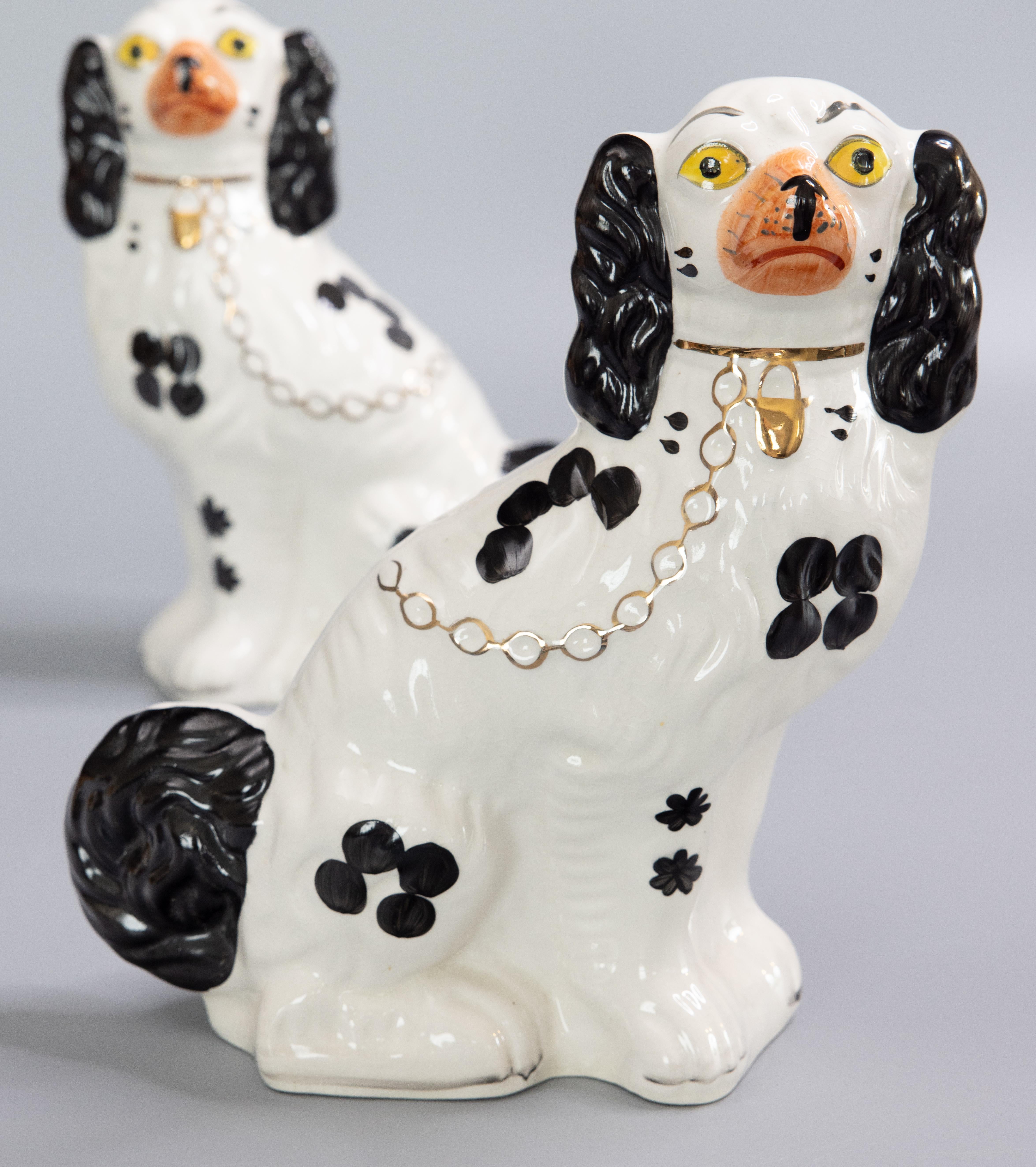 A fine pair of early 20th century English Staffordshire black and white spaniel dog figurines. These hand painted dogs have gorgeous gilt details, sweet faces, and are a nice large Size. These charming fellows would be a wonderful addition to a