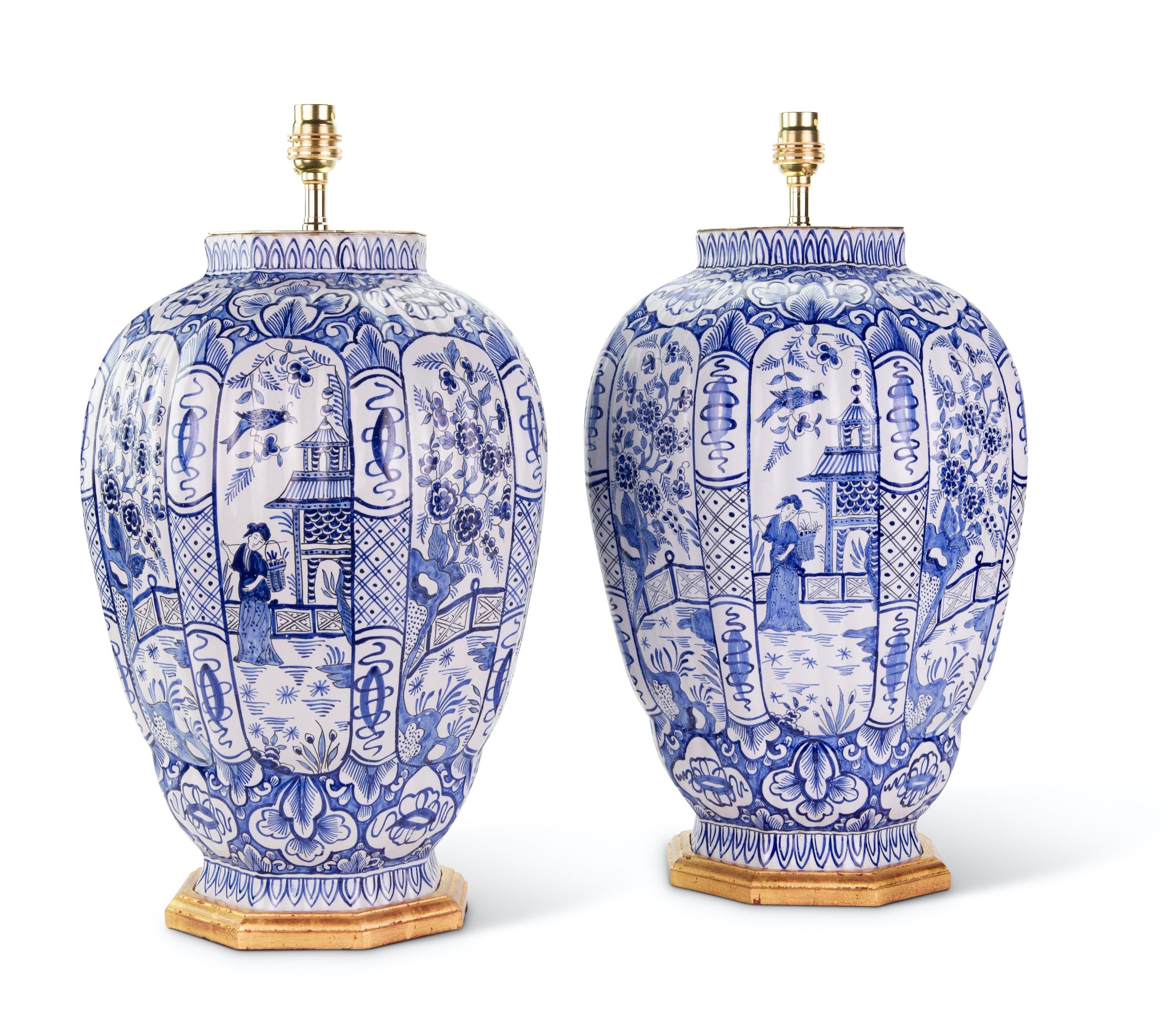 A fine pair of large Dutch Delft blue and white vases, with octagonal gadrooned bodies, decorated in tones of blue on a white background, with panels of courtly figures in garden scenes with pavilions and birds, with further stylised