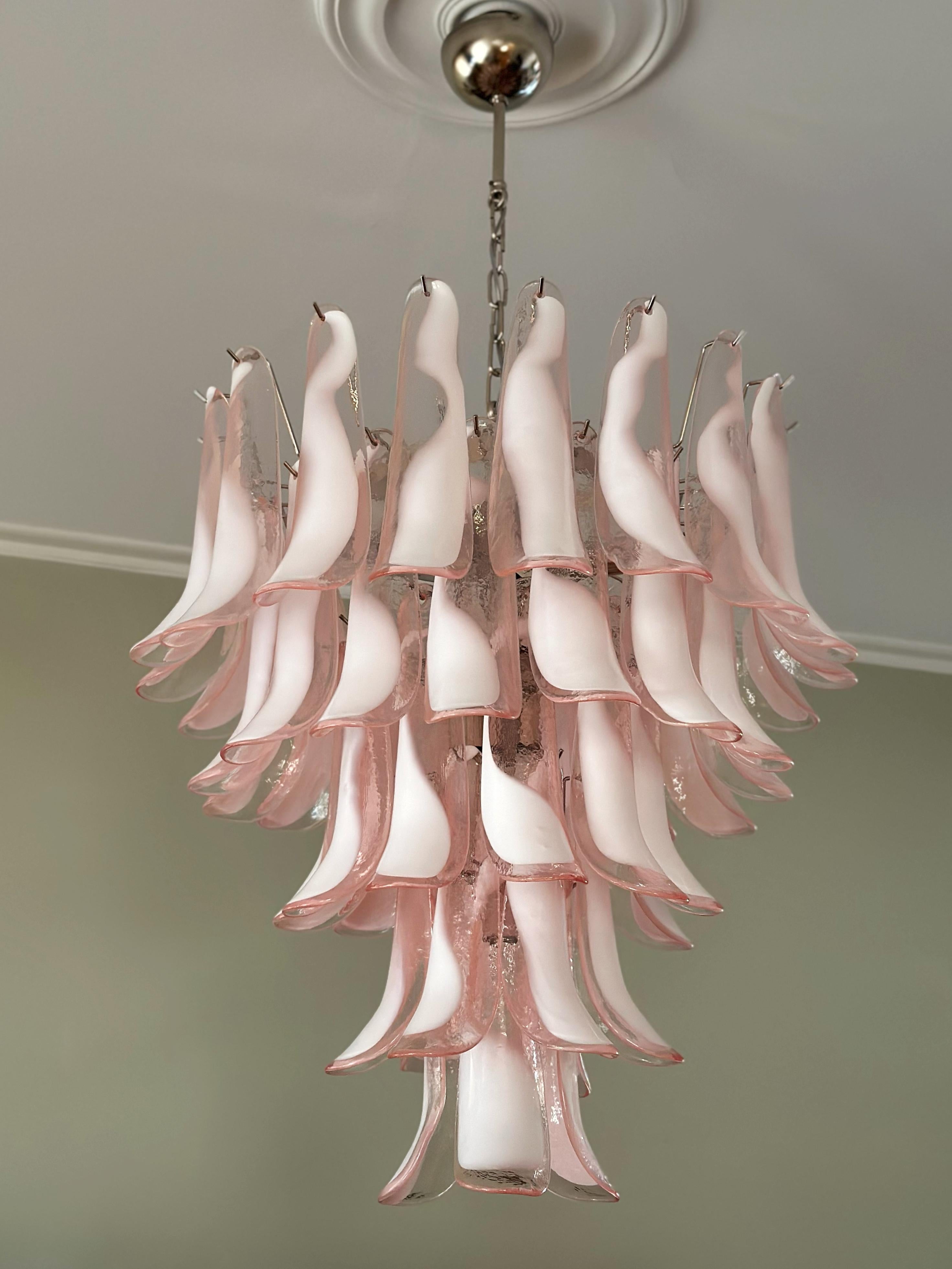 Paire de lustres Murano roses, audacieux et éclectiques. Prismes en verre formés de pétales dans le style italien traditionnel du milieu du siècle. Les pétales en verre présentent des tourbillons en verre blanc, rose et transparent.
Le luminaire