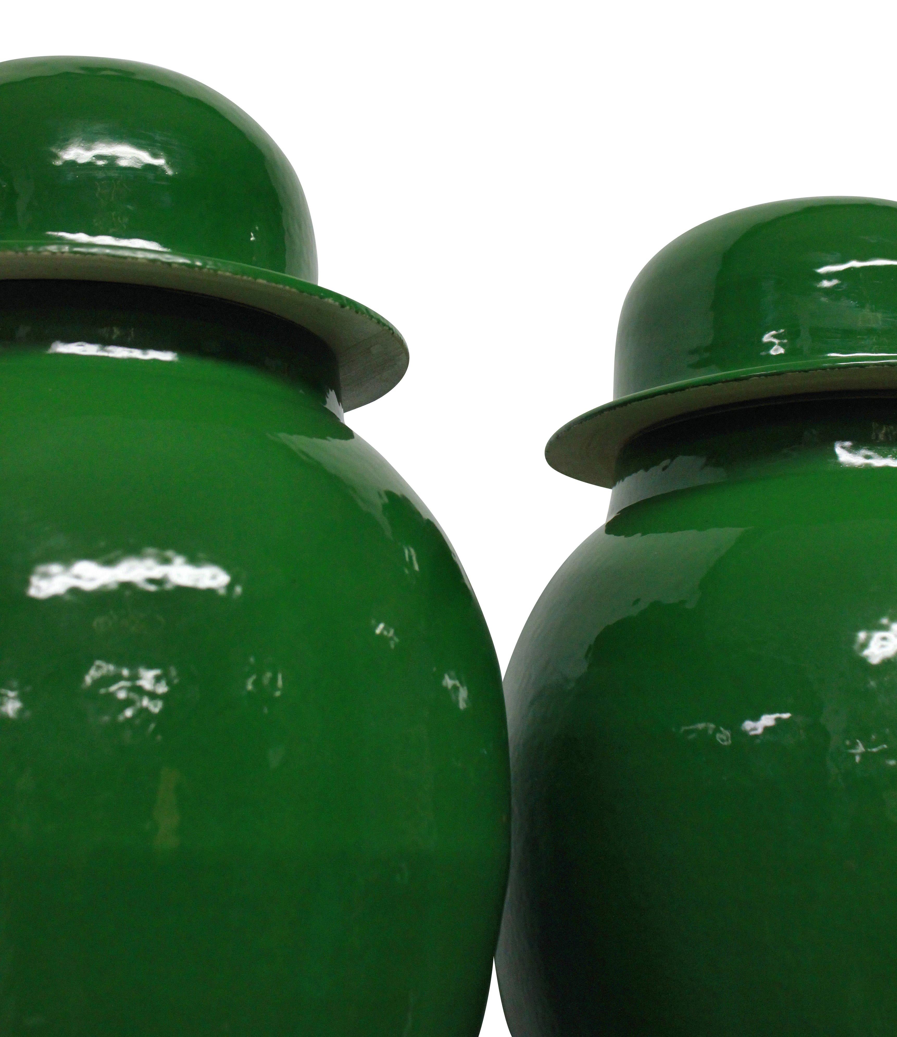 A pair of large emerald green Chinese glazed vases with covers and brass detail to lid.