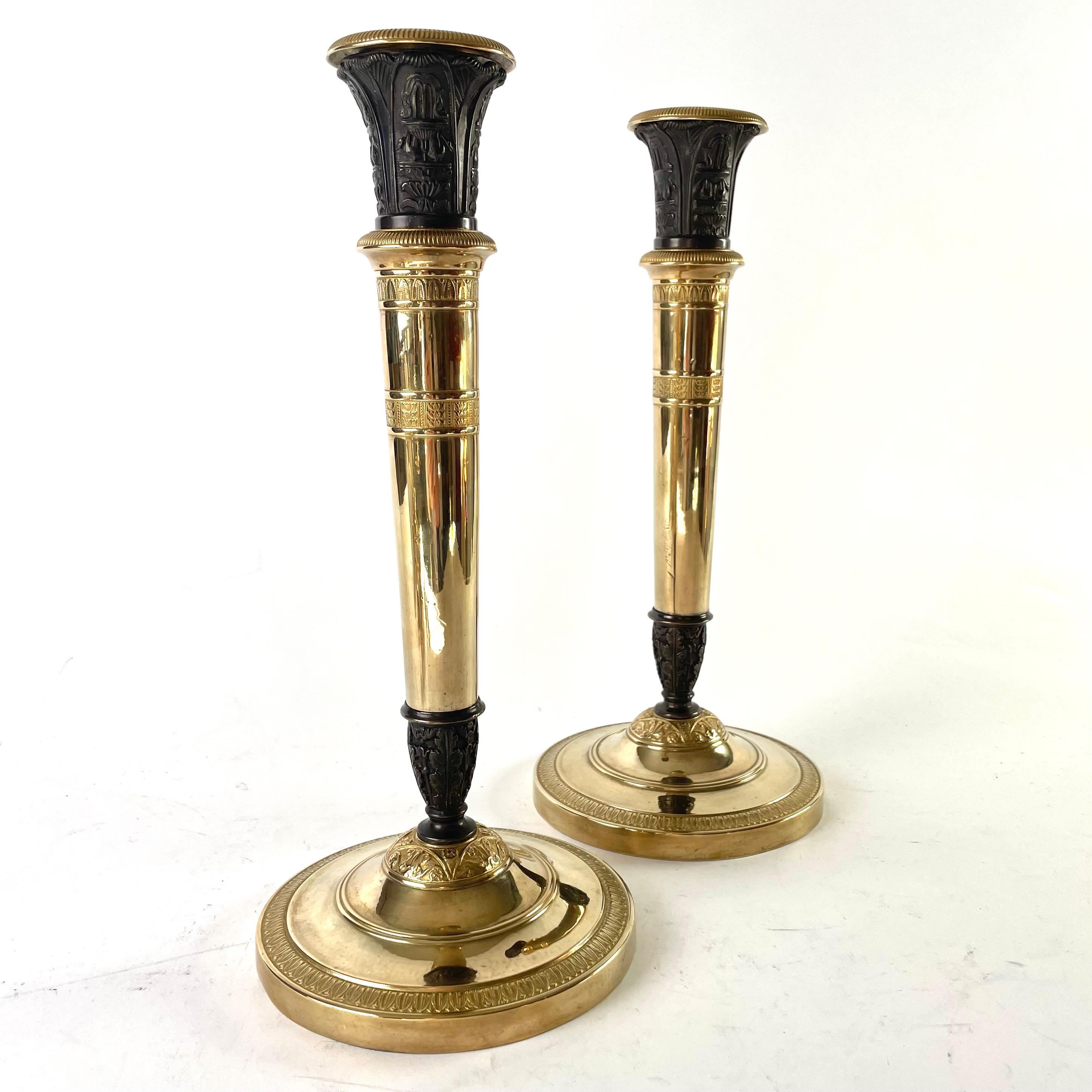 A pair of large and elegant Empire Candlesticks, convertible into Candelabra, made in France during the 1820s. Gilded and dark patinated bronze. Can be used as large candlesticks or as three-armed candelabra. The height with the candelabra arms is
