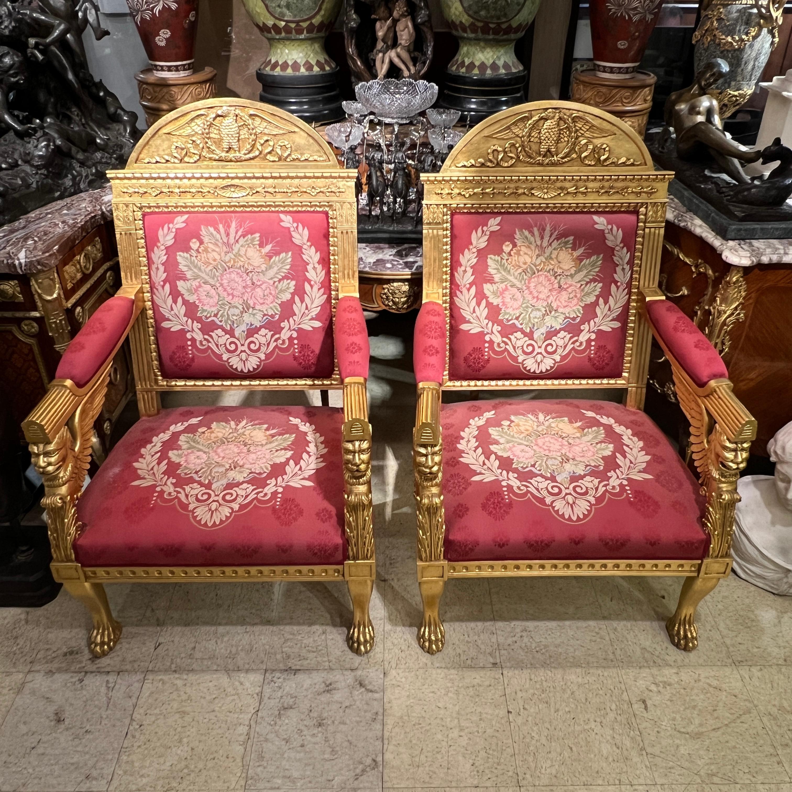 Pair of vintage (20th century) hand-carved giltwood armchairs in the French  Empire style with lovely red upholstered seats, seatbacks and armrests with petit point embroidered floral decorations.