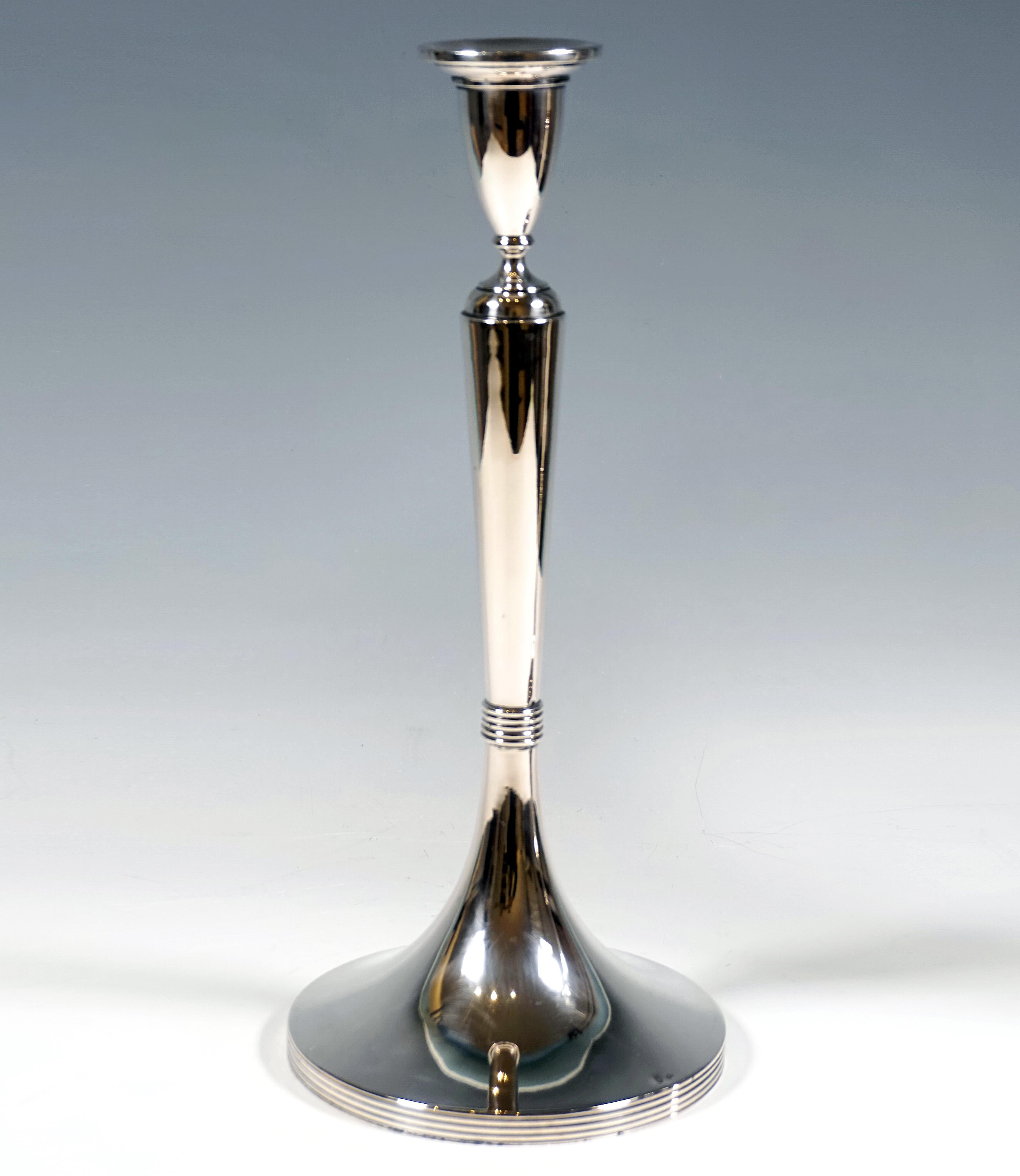 Two large, elegant, simple silver candlesticks on a round base, round foot grooved on the sides, smooth shaft raised in the centre with a profiled constriction, shaft widening conically towards the top, topped with elegant, raised vase-shaped spout