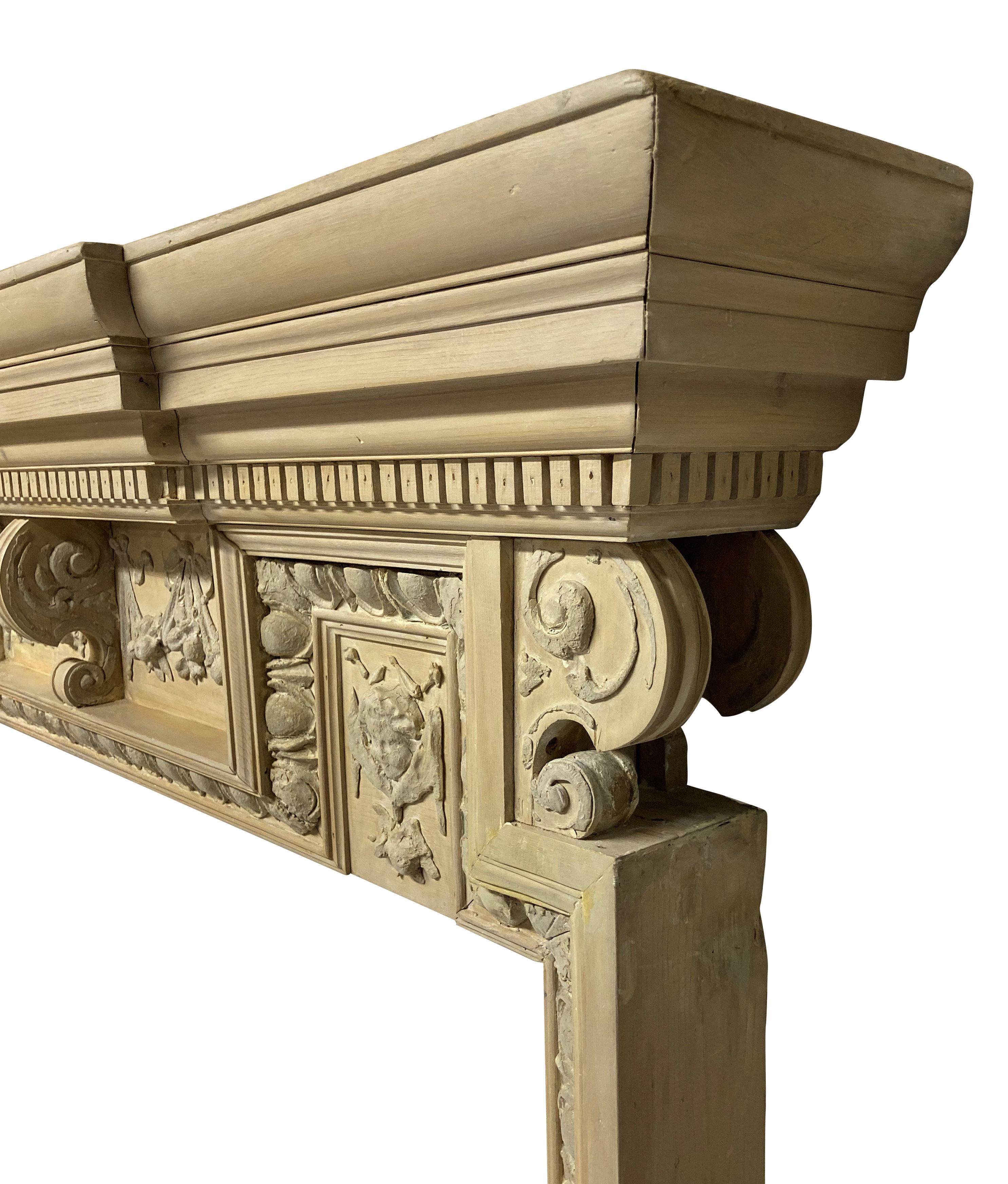 A pair of large English 18th century pickled pine and composition fire surrounds. With egg and dart moulding, swags, scrolls and cherubs. Probably pickled in the 1930s, when it was fashionable. Illustrated is one of two dozen 18th century cut iron