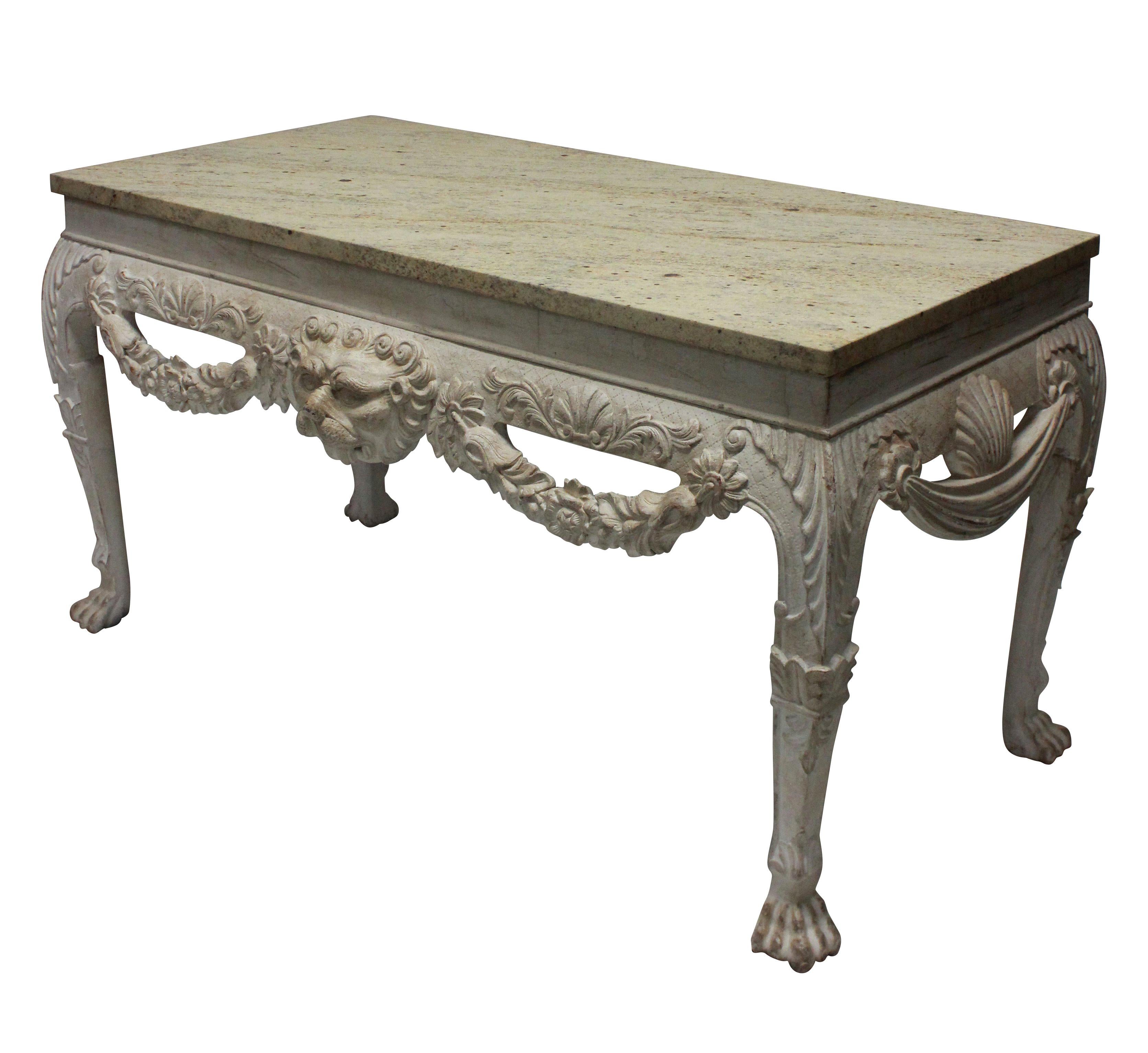 A large pair of English Country House console tables in the 18th century manner, with lion masks, swags and acanthus carvings. Distressed painted mahogany with stone coloured marble tops.

 