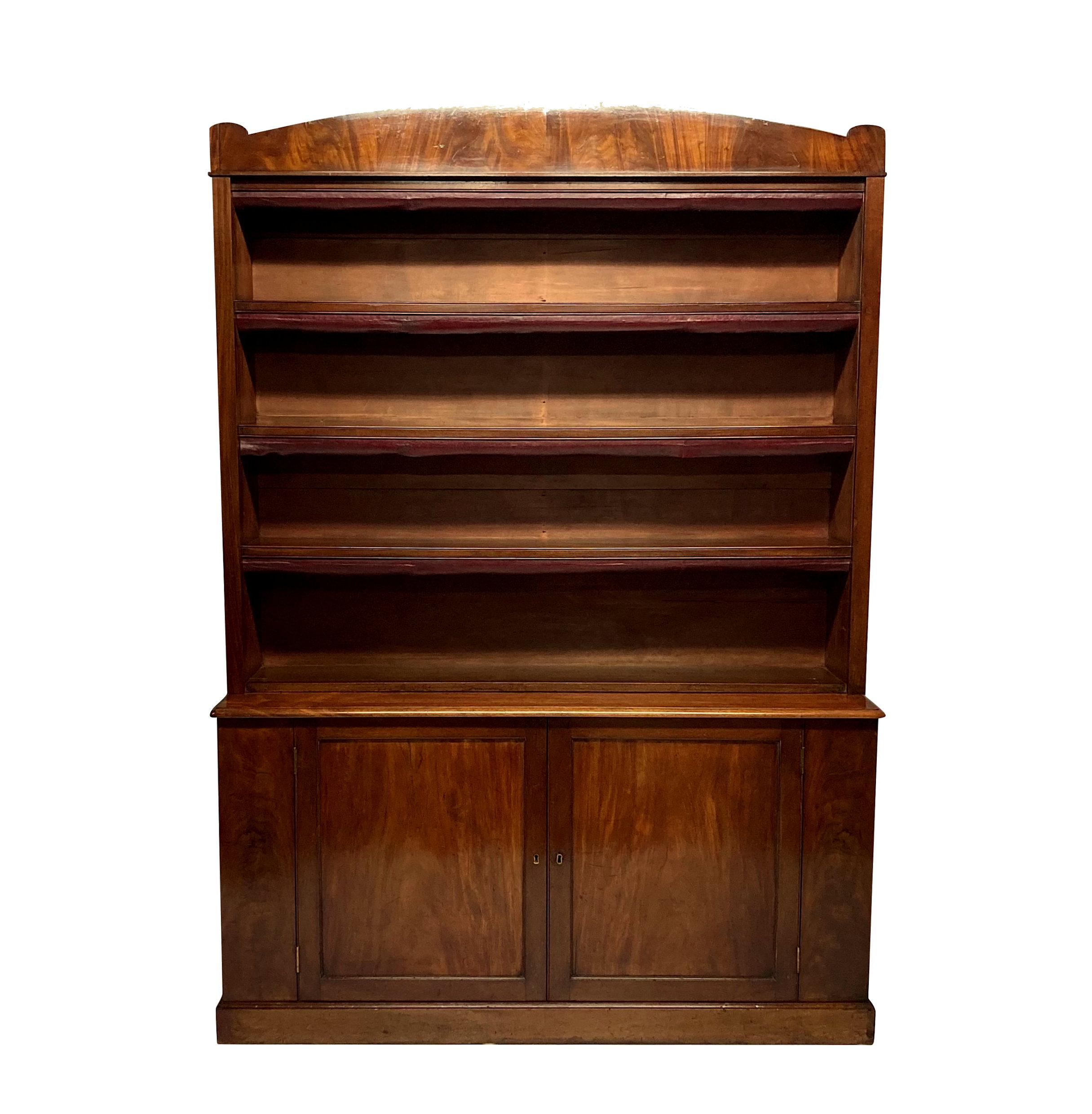A pair of large English architectural mahogany bookcases, each with three fixed shelves with burgundy leather edging. The cupboards below, each with a single shelf and a restrained arched pediment reminiscent of Lutyens work.

Measure: 163 & 170cm