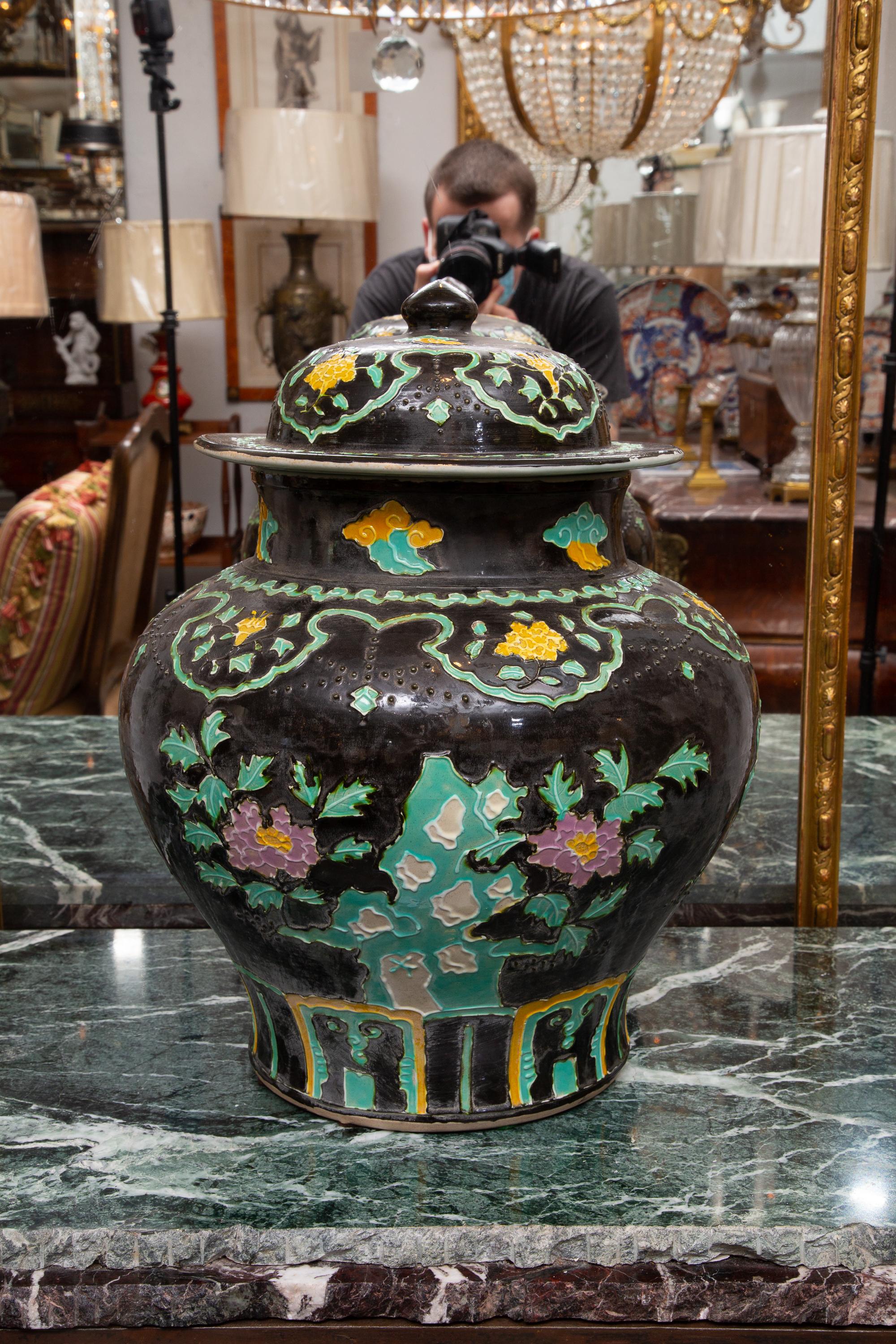 A magnificent pair of Chinese lidded Fahua pottery lidded jars, the black background painted over-all with flowers and foliage in relief form.