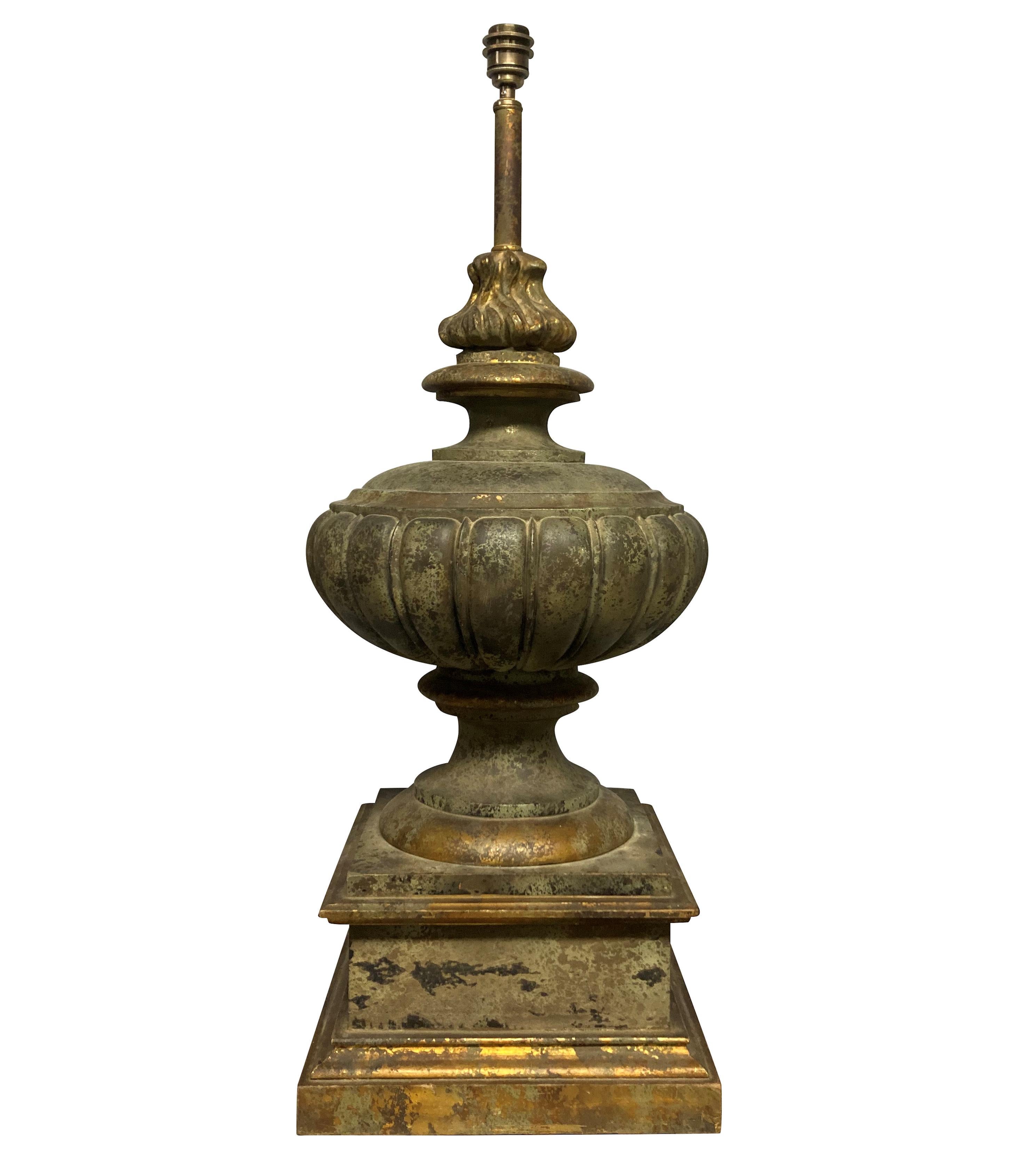 A pair of large English faux bronze Classical urn lamps, on plinths, with flambe finials. Painted and gilded.