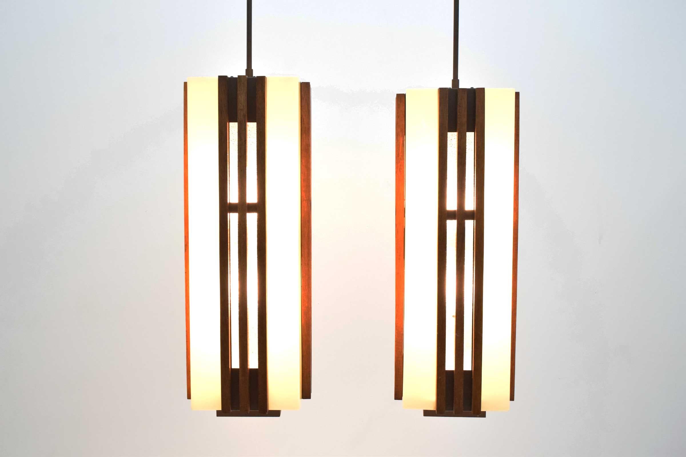 This is a gorgeous pair of large Frank Lloyd Wright style chandeliers or pendants. Lights are very well make and have a strong metal rod and frame that support plastic shades. Outside has rods of walnut on all four sides of each light. There are 6