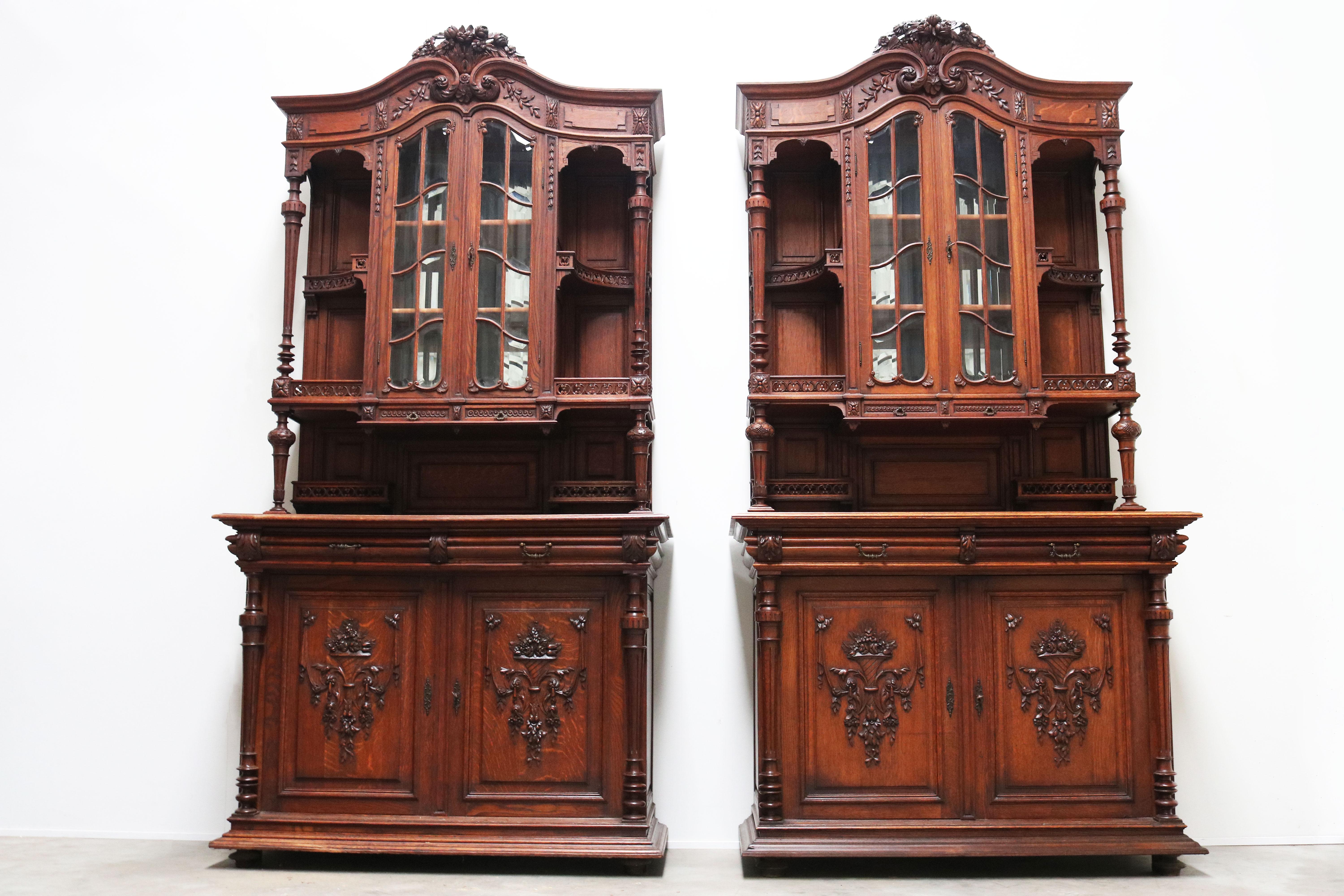 Simply stunning! This pair of French renaissance revival buffet cabinets from the 19th century. 
Both cabinets are made out of solid oak with 16 beveled glass windows & 1 beveled mirror on the backside. 
Amazing quality with many detailed carvings
