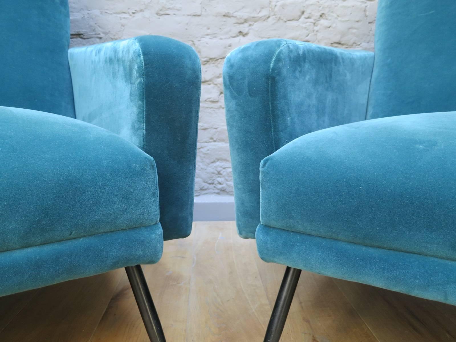 Re upholstered in teal velvet, this angular pair of armchairs with their simple, clean line design, typical of that era.