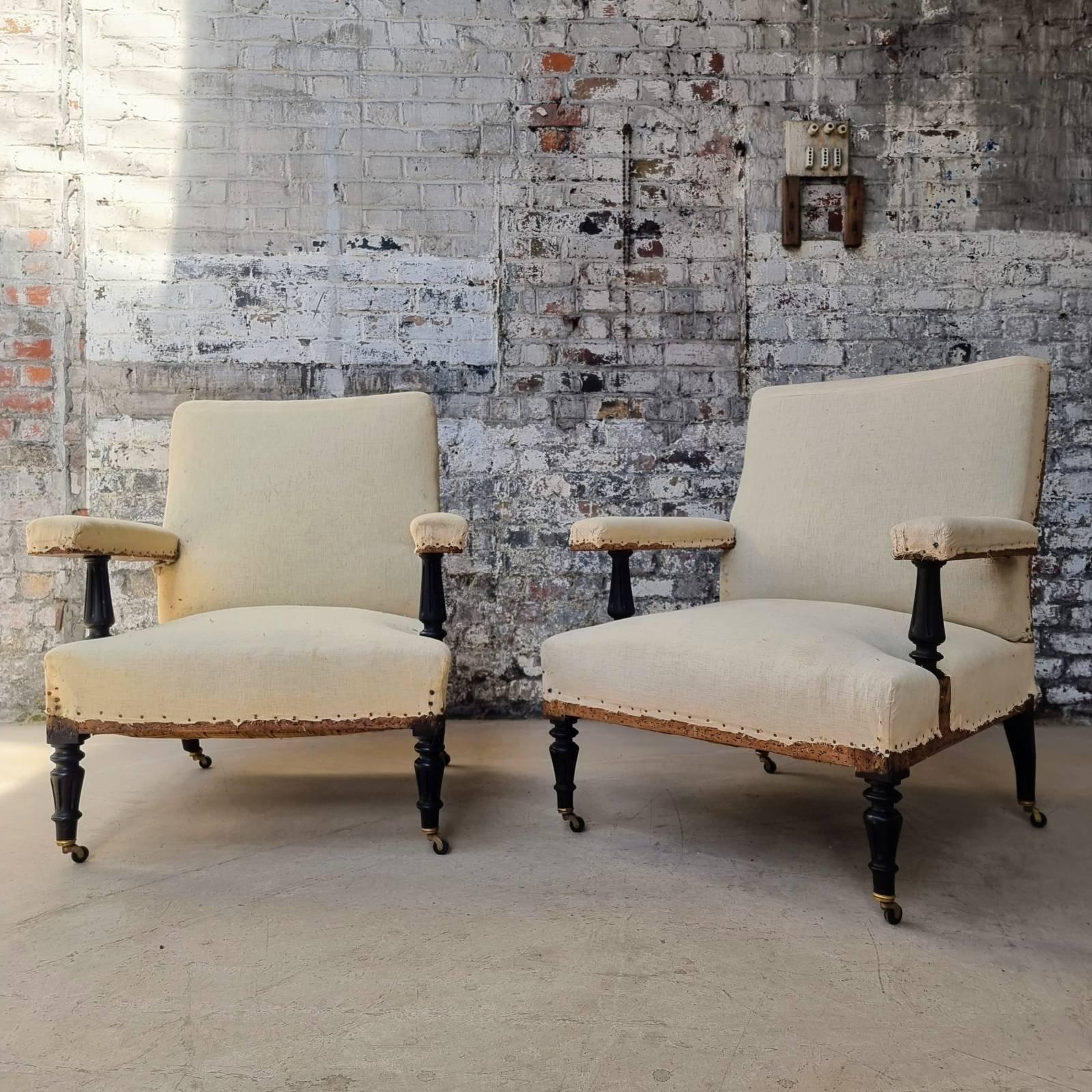 An unusual pair of French Napoleon III armchairs having exposed wooden arms and classic turned legs. The large seat and back make these chairs very comfortable. The chairs have been stripped down to the muslin, but are ready to be upholstered. We