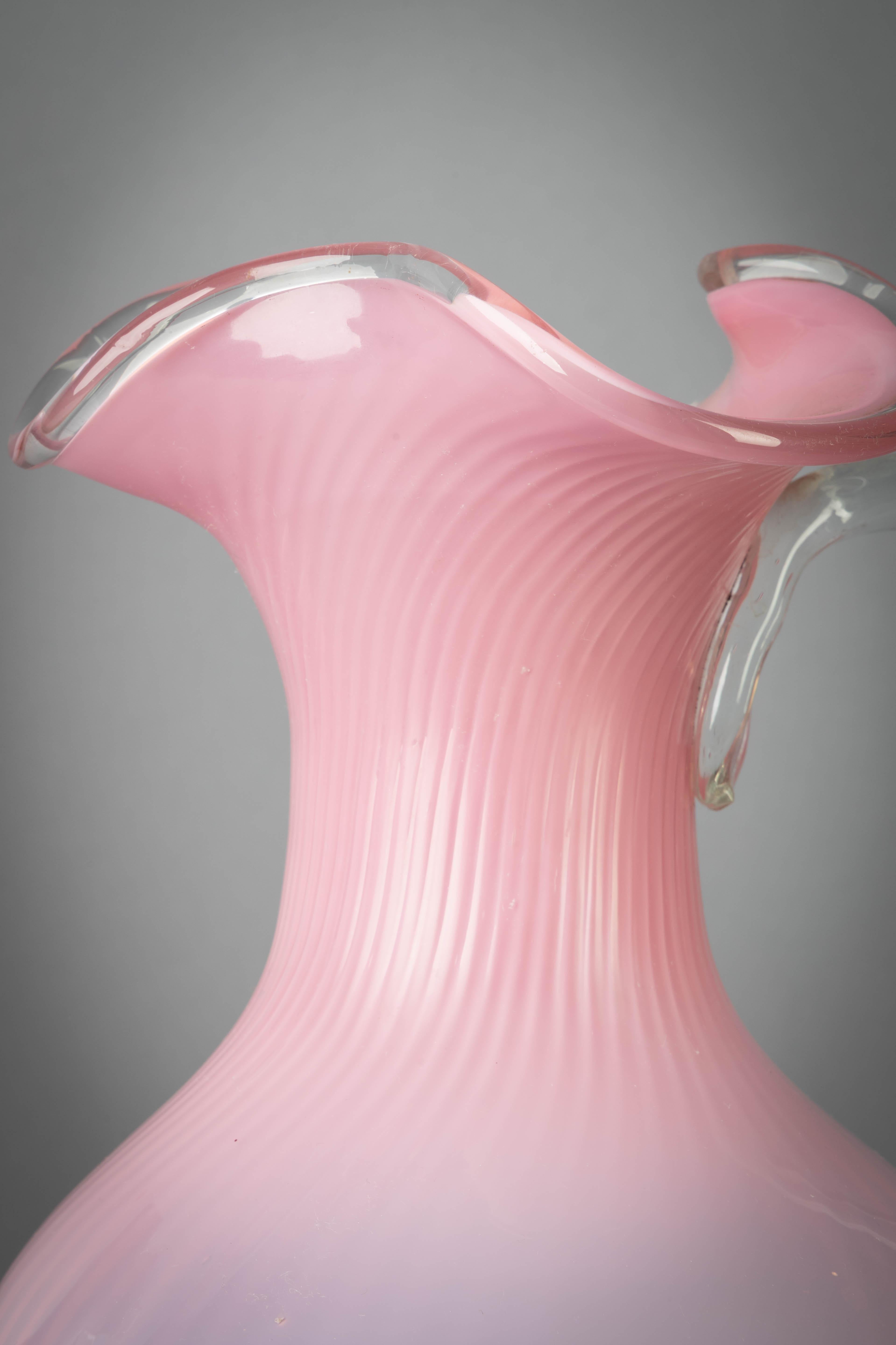 Each of spiral-fluted form with trefoil necks and applied clear glass handles, on circular bases.