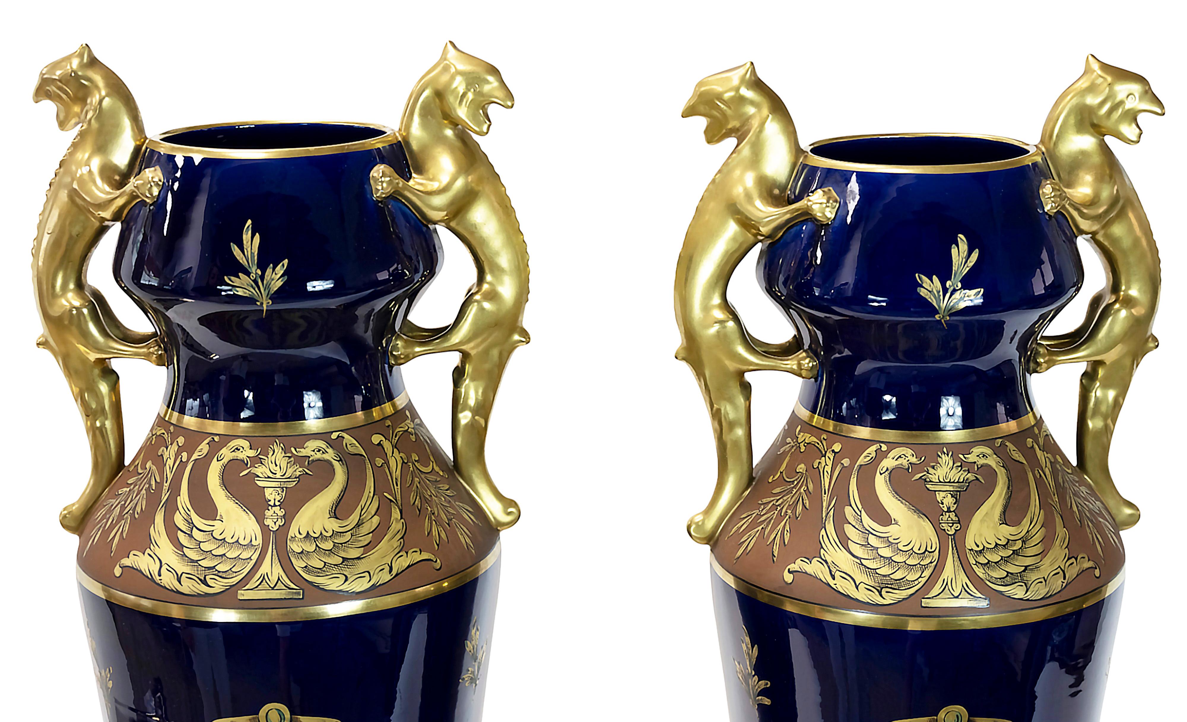 Pair of French amphora form glazed porcelain cobalt blue vases decorated with floral and birds elements in gold decor. Gilt handles are in the form of iguana. 
Created by Maurice Pinon and made by Jaget & Pinon Manufactory in Tours.
Marked on the