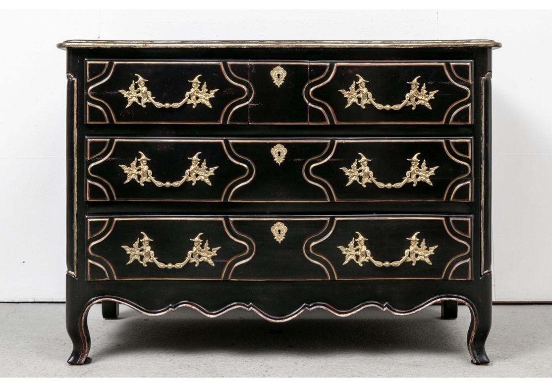 A pair of very decorative large French style chests in black finish with antiqued gilt top edge and carved drawer details. The Chests, with a Grand Hollywood Regency style presence, each have three long drawers with shaped panels mounted with brass