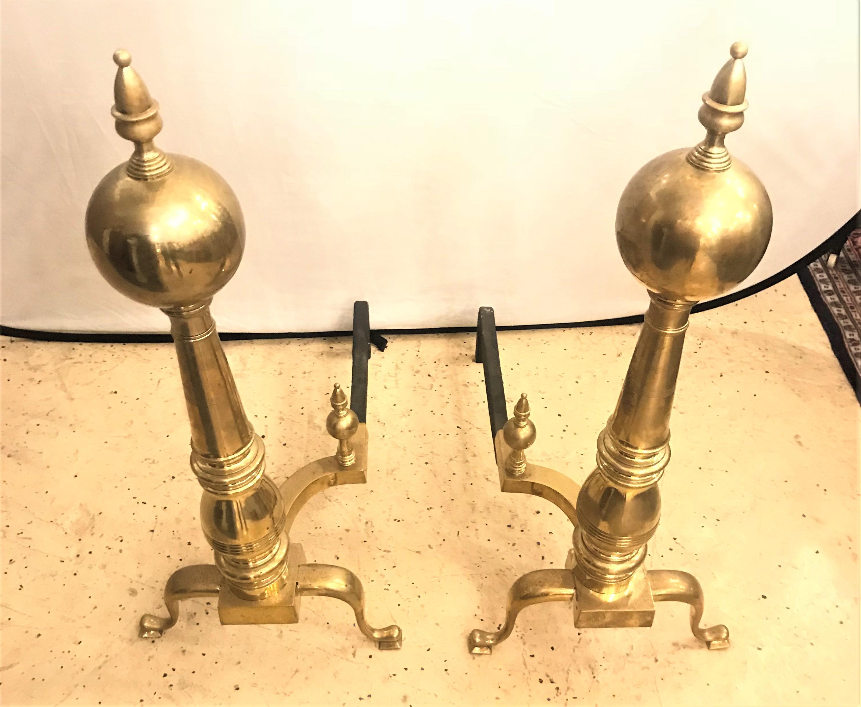 A pair of large Georgian style brass andirons. Each having the claw foot single column form pedestal leading to a large upper sphere terminating in a finial as was so typical in the Georgian error. Clean and without damage. This palatial pair are