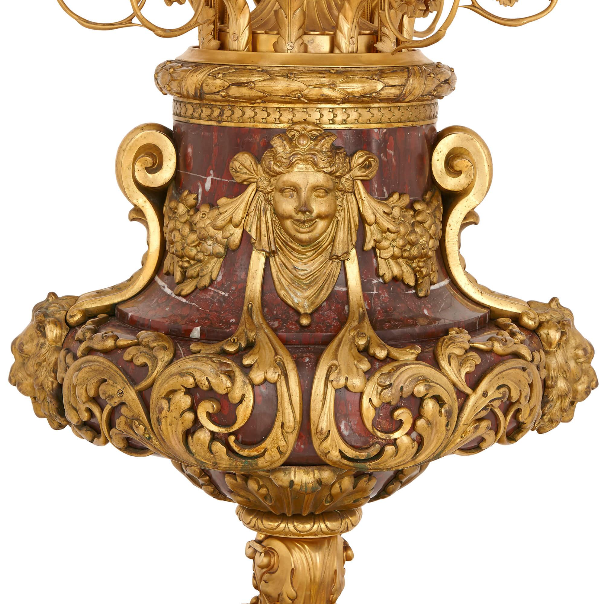 Cette exceptionnelle et grande paire de candélabres en marbre rouge et bronze doré est opulente, avec des décorations de style néoclassique finement moulées. Chaque candélabre est formé d'un vase en marbre rouge sur une base en bronze doré, avec