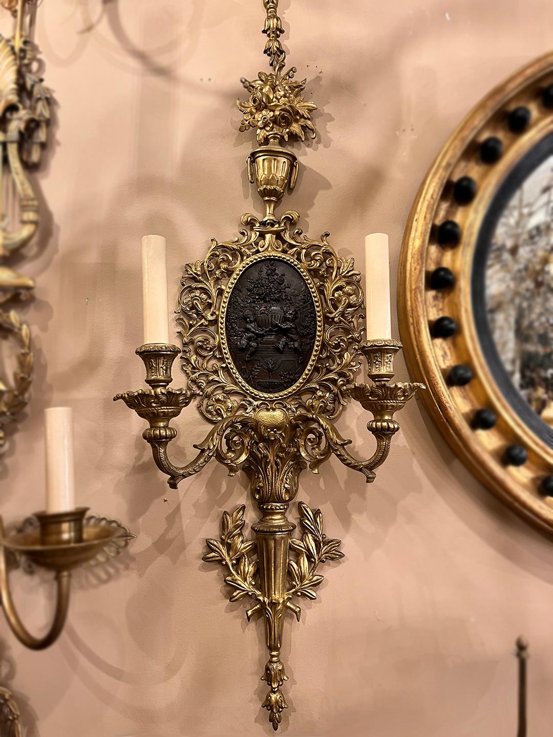 A pair of circa 1900 French sconces in gilt bronze with a patinated bronze central medallion.

Measurements:
Height 28.5