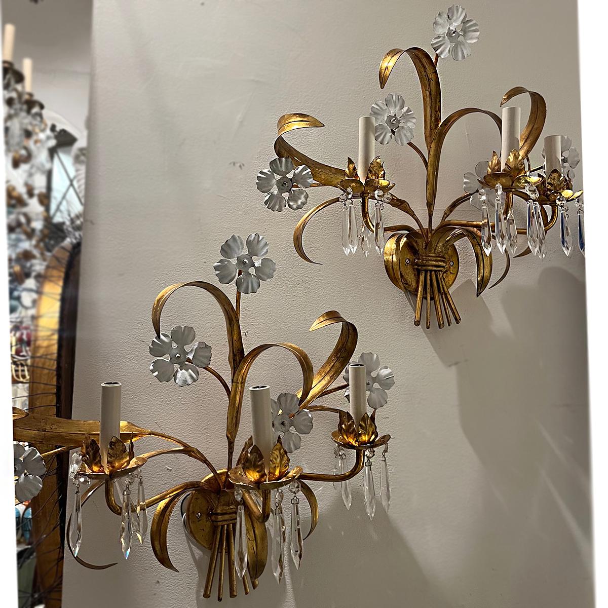 Paire d'appliques italiennes des années 1940 en métal doré et fleurs blanches avec gouttes de cristal.

Mesures :
Hauteur : 20″,
profondeur : 10″,
largeur : 21″.