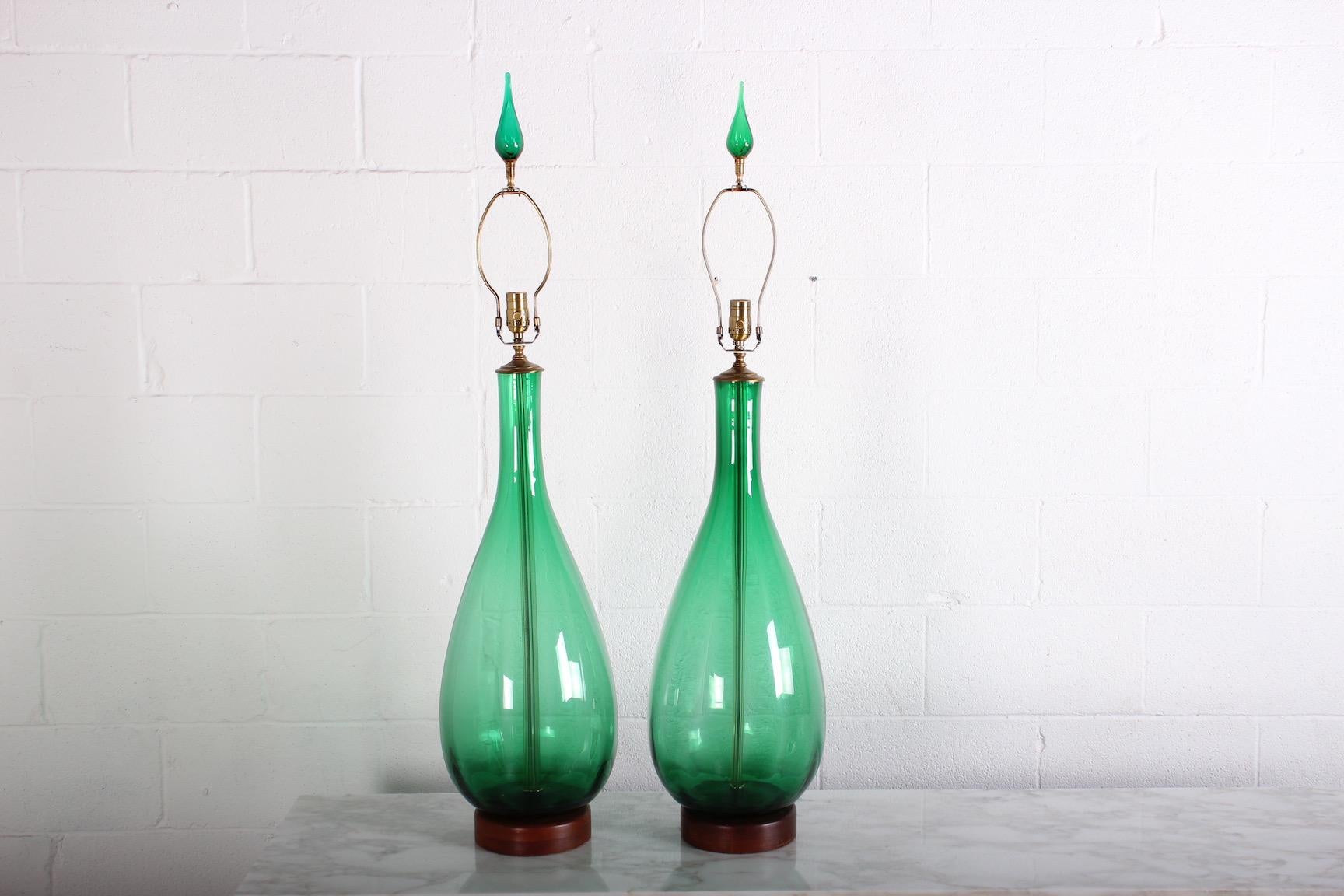 A large scale pair of green glass lamps with matching finials by Blenko.