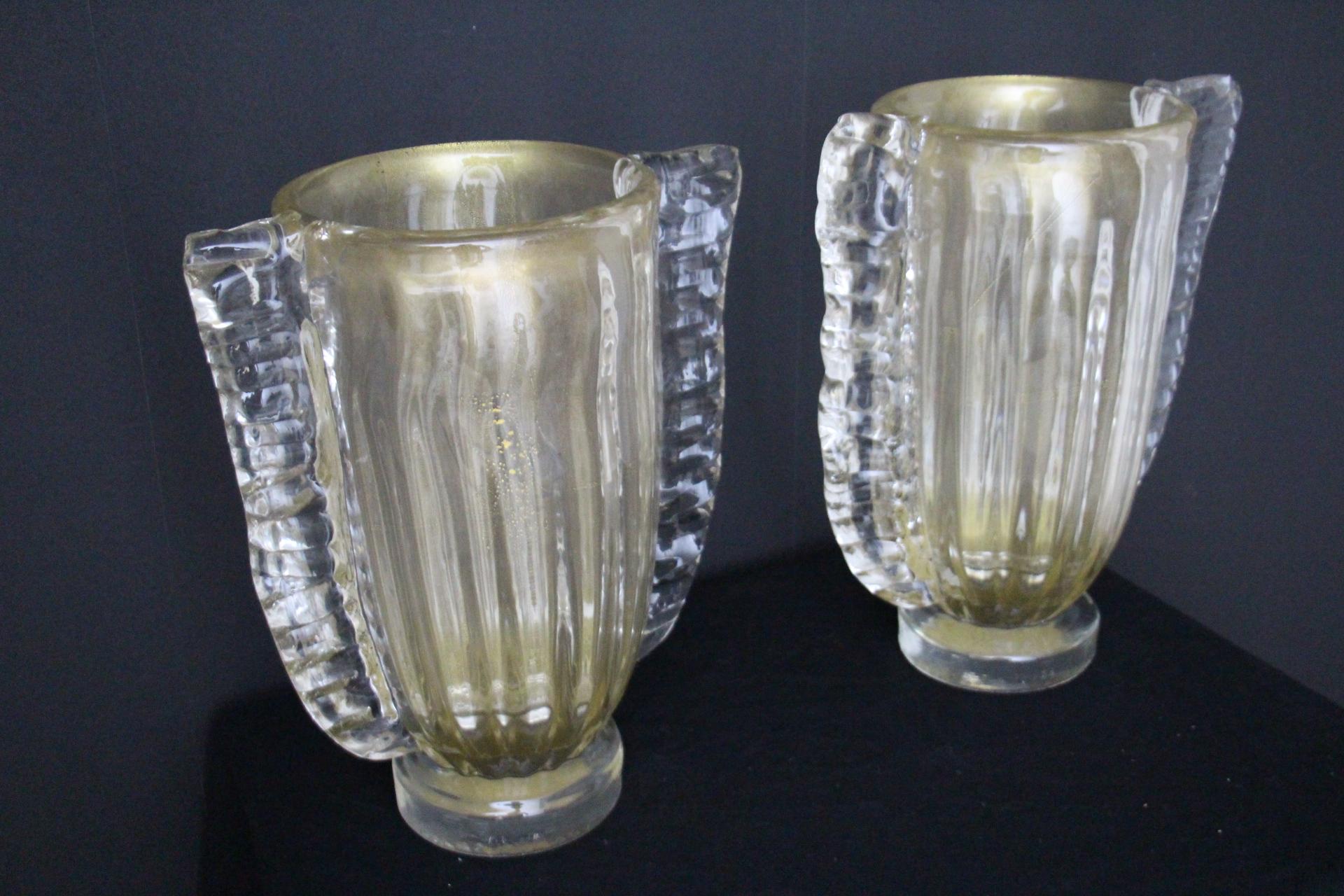 This spectacular pair of vases has got a very unusual golden according to surrounding colors and light. This special effect is due to deep gold dust inclusions in glass.On each side, they feature generous glass scallops in crystal color.Their