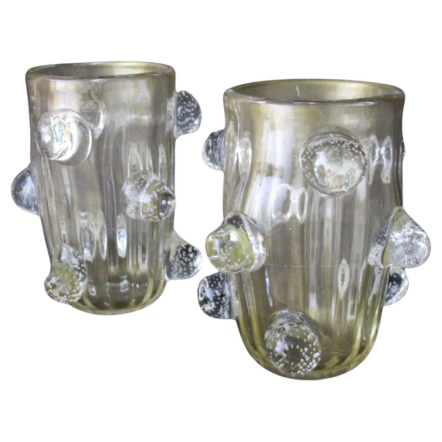 This spectacular pair of vases has got a very unusual golden color that goes from deep beige to light gold according to surrounding colors and light. This special effect is due to gold dust inclusions in glass.Glass is very deep and each bubble