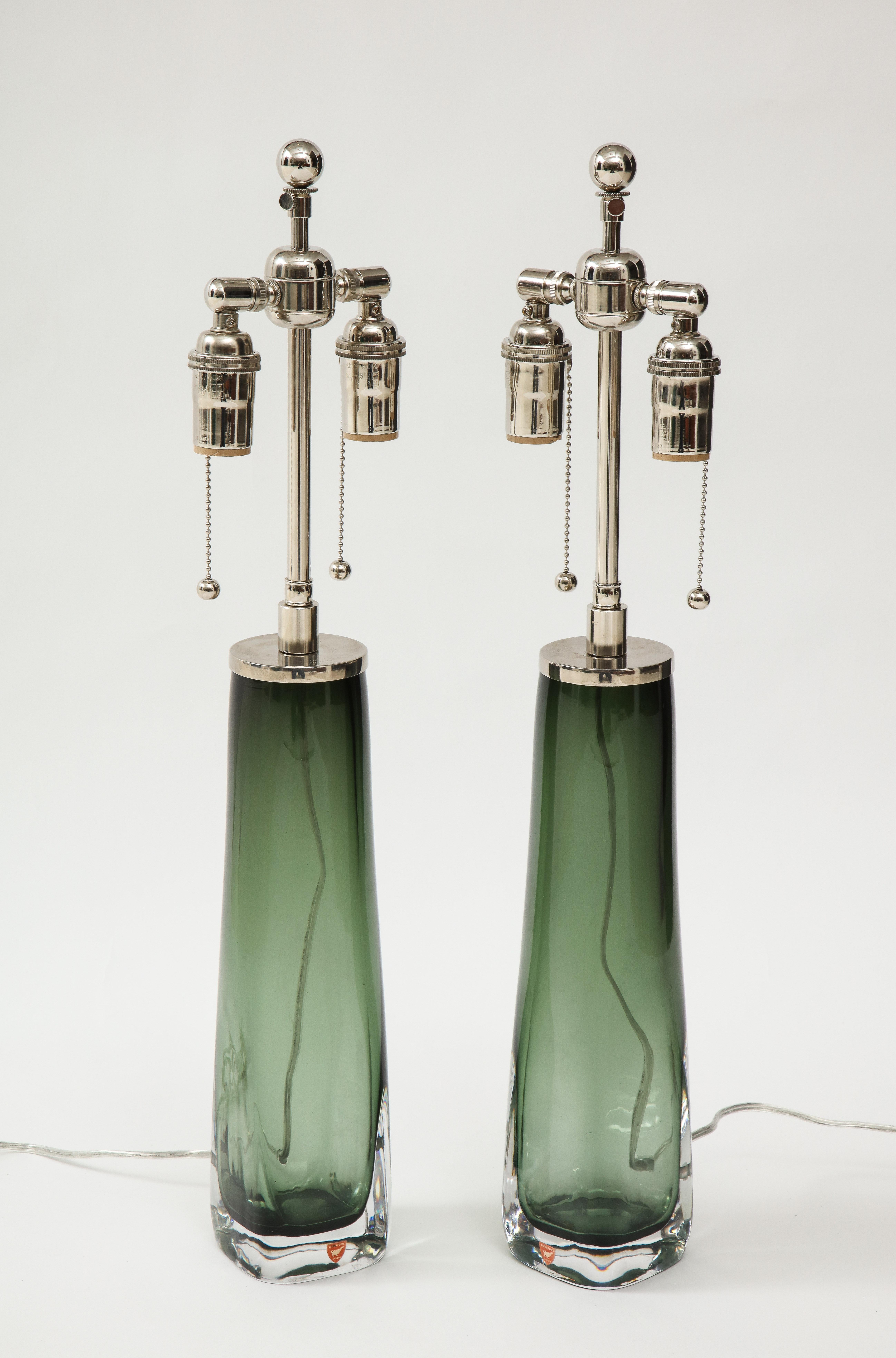 Pair of 1960s sleek glass lamps by Carl Fagerlund for Orrefors.
The beautiful green transparent glass lamps have been newly rewired for the US
with adjustable polished chrome double clusters that take standard size light bulbs.
They retain there