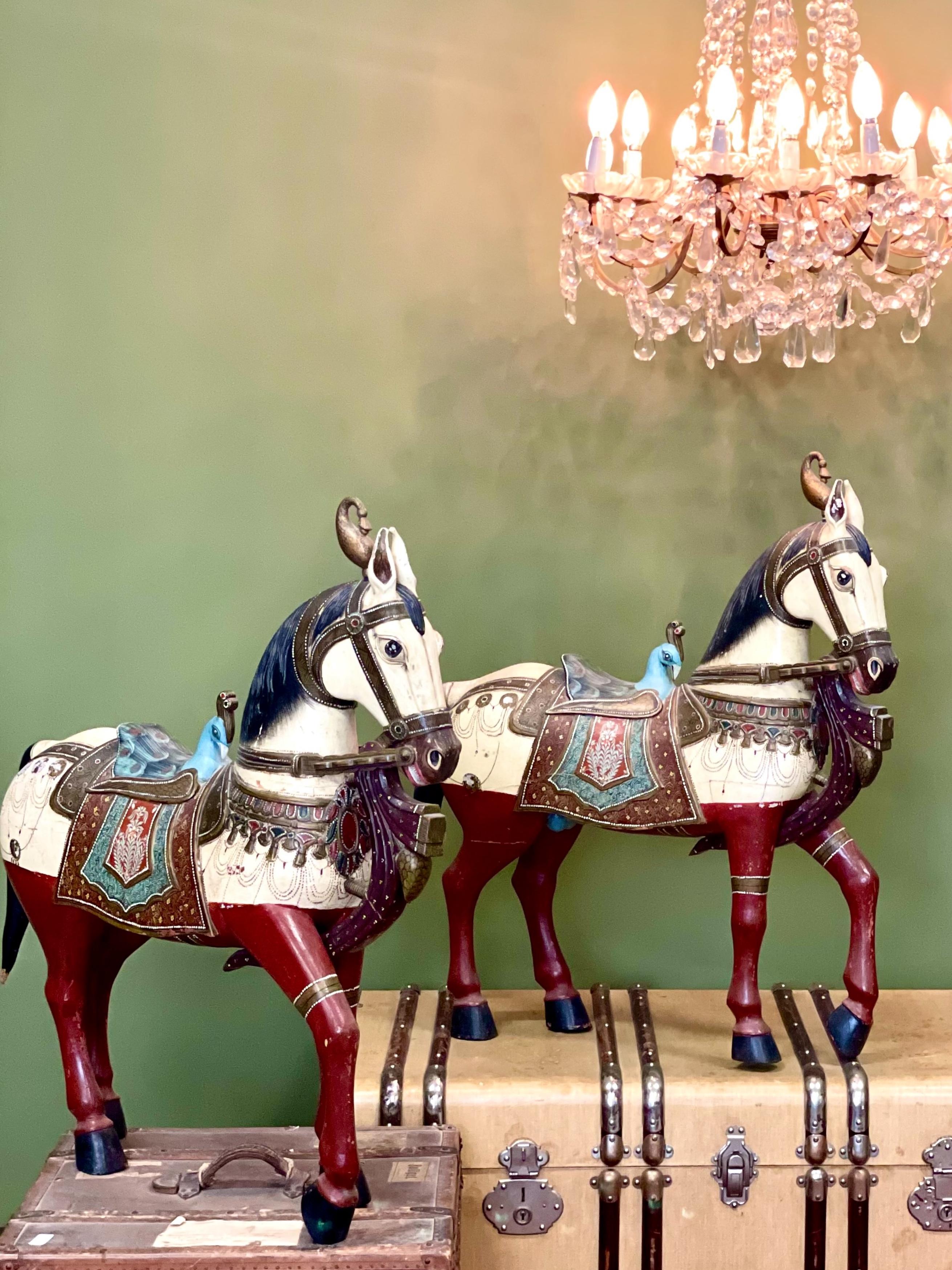 Questa eccezionale e imponente coppia di cavalli in legno intagliati e dipinti a mano incarna il ricco patrimonio artistico dell'artigianato tradizionale indiano. Con oltre 80 cm di altezza e altrettanti di lunghezza, questi pezzi maestosi sono in