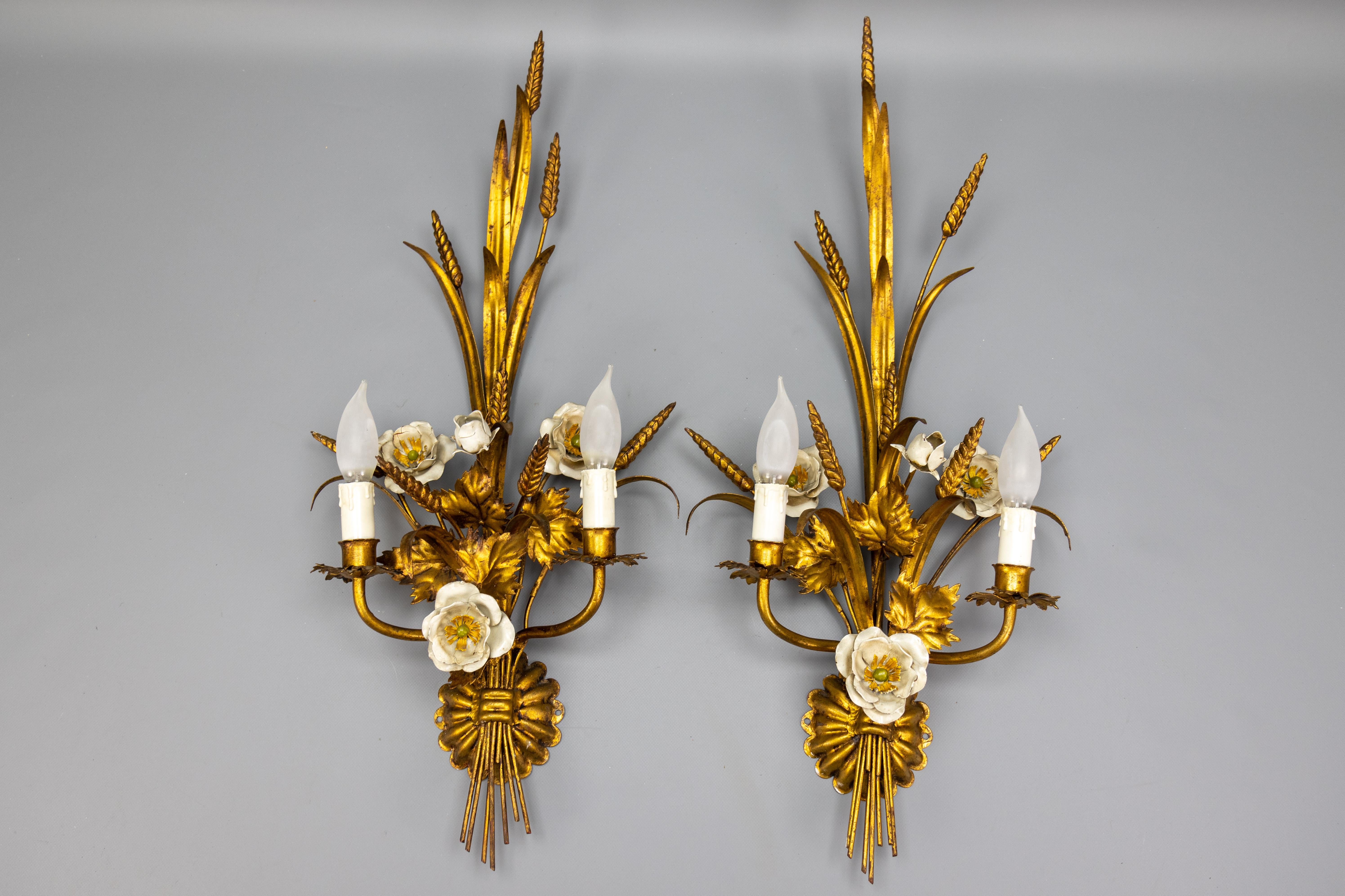 Pair of Large Hollywood Regency Gilt Metal Wheat and White Flower Sconces, 1970s

A striking pair of Hollywood Regency-style wall sconces, crafted in Italy during the 1970s. These sculptural light fixtures feature an elegant arrangement of gilded