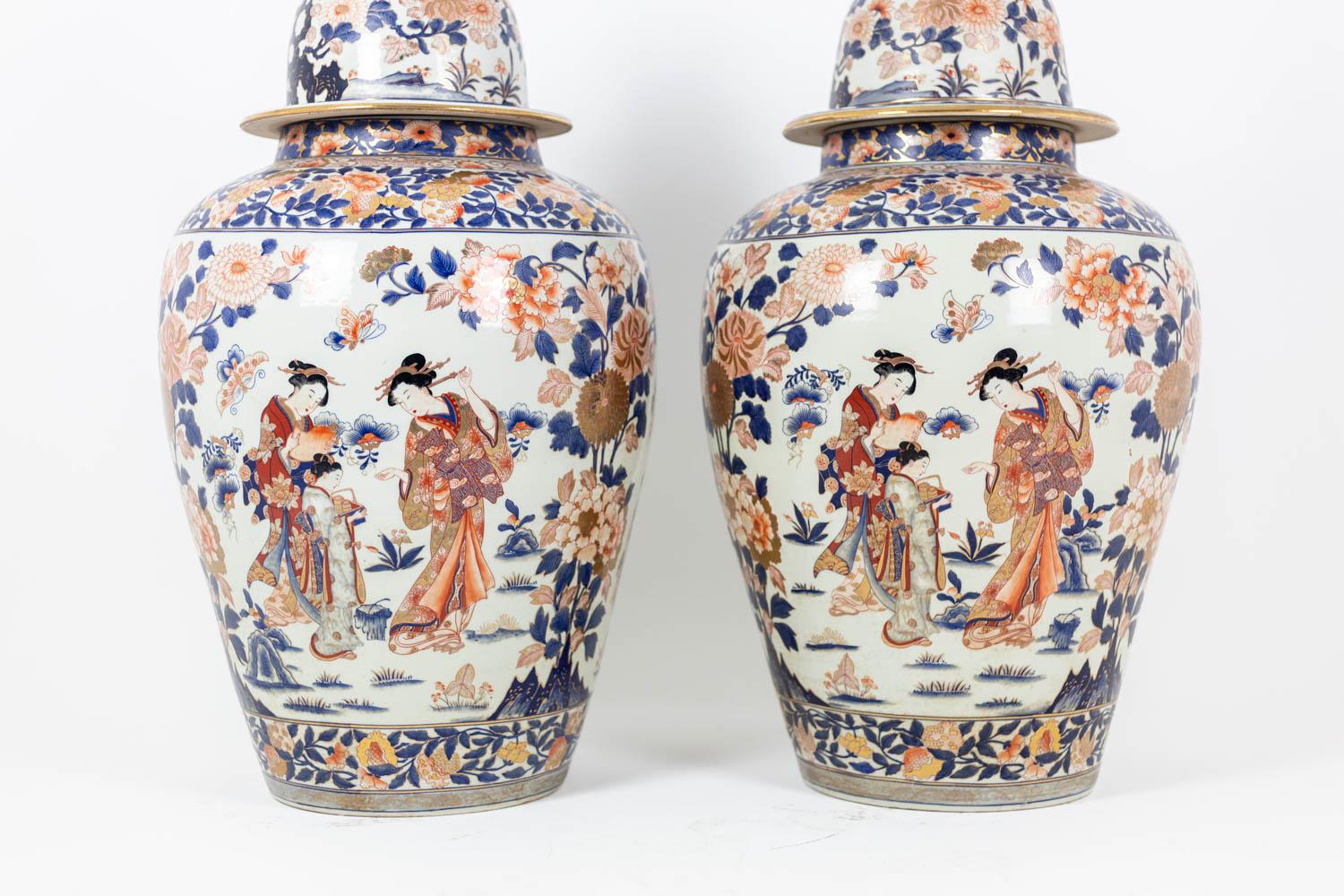 Pair of large porcelain vases with Imari decoration. Panse decorated with figures of geishas and other floral motifs in the background. Floral frieze in blue, white and red. The vases are covered with pots.

Work carried out circa 1900.