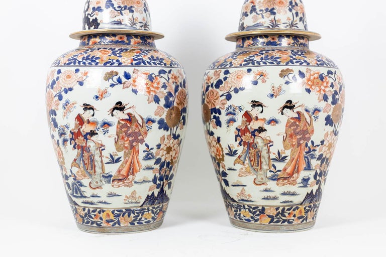 Pair of large porcelain vases with Imari decoration. Panse decorated with figures of geishas and other floral motifs in the background. Floral frieze in blue, white and red. The vases are covered with pots.

Work carried out circa 1900.