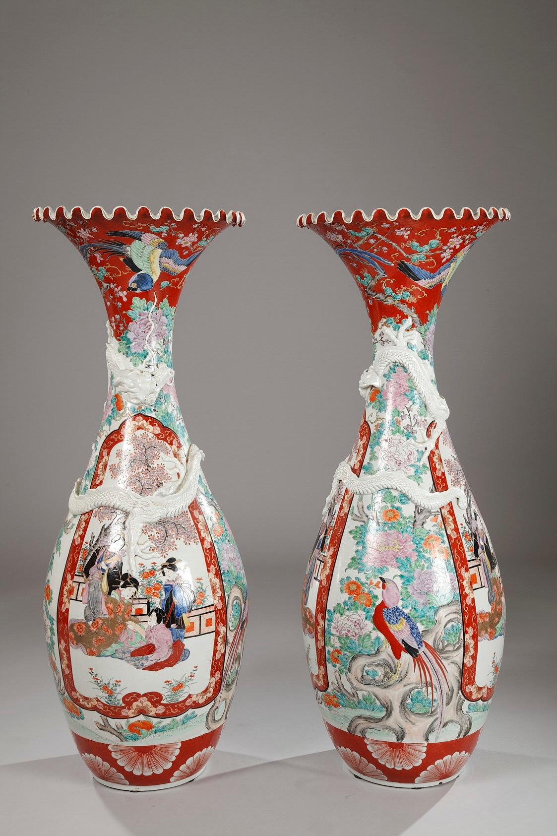 Très belle paire de vases en porcelaine d'Imari, de forme effilée avec un sommet évasé. Décor d'oiseaux et de fleurs polychromes sur fond blanc. Le corps est peint de panneaux façonnés représentant des scènes de cour figuratives. Un dragon en relief