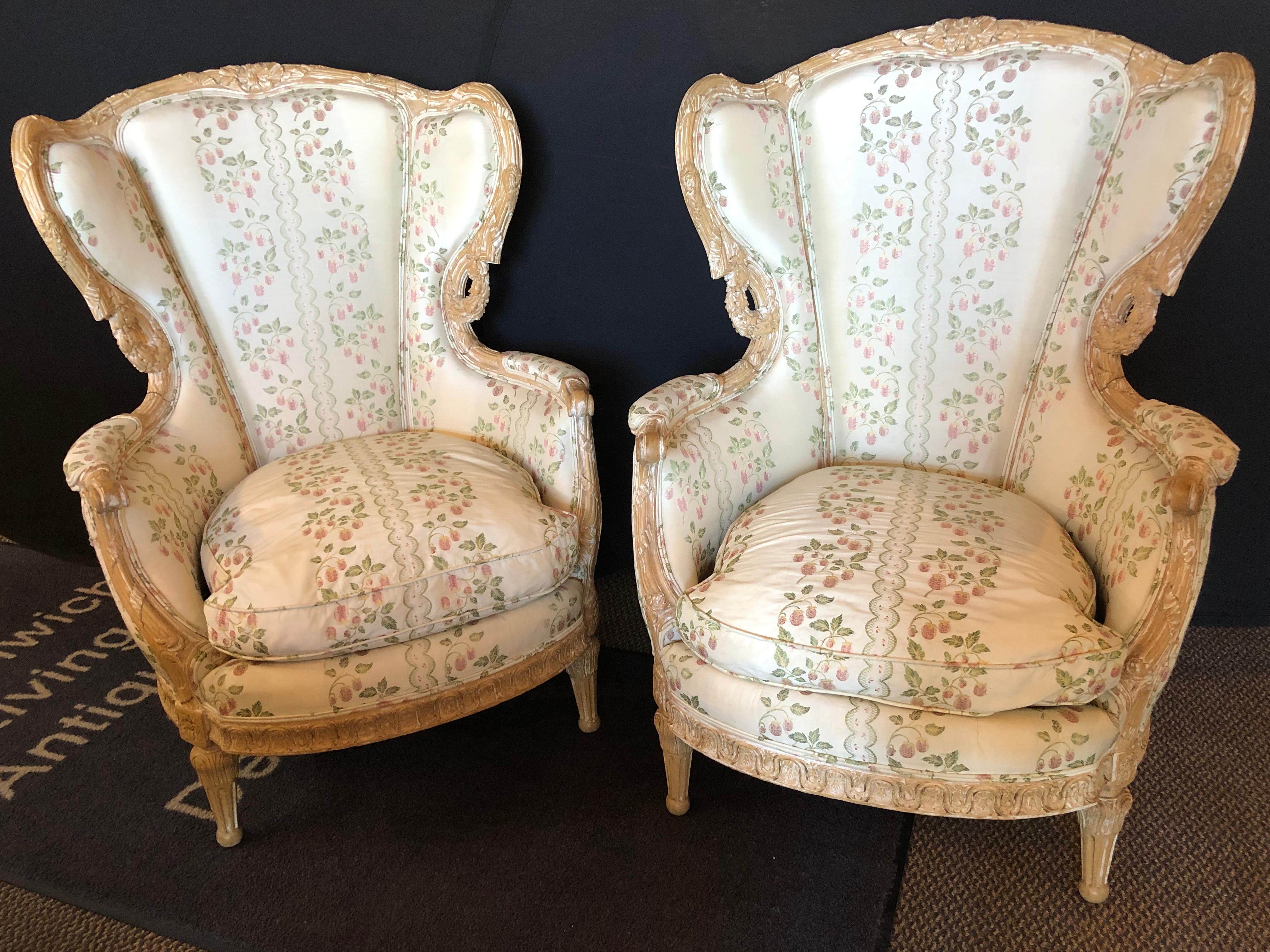 Pair of large impressive high back distressed carved framed wing back armchairs in a fine fabric.