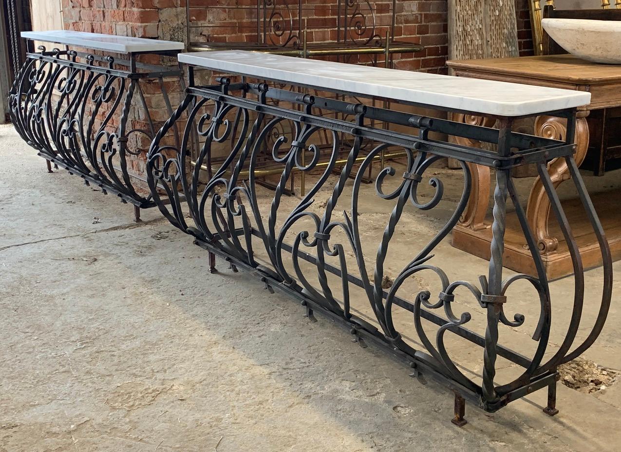 A beautiful pair of French wrought iron and marble console tables. The iron bases still have their original paint which is worn in places. With a solid Carrara marble tops. Made in the first quarter of the 20th century.