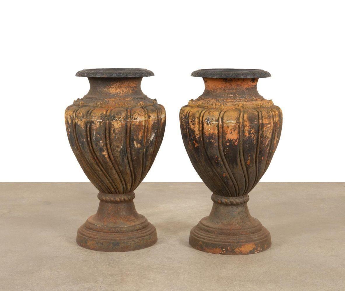 Pair of large rustic cast iron garden urns made in Italy in the 1900's; each adorned with gadroon motifs all around as well as a layered base design that supports each urn.
Dimensions:
35.5