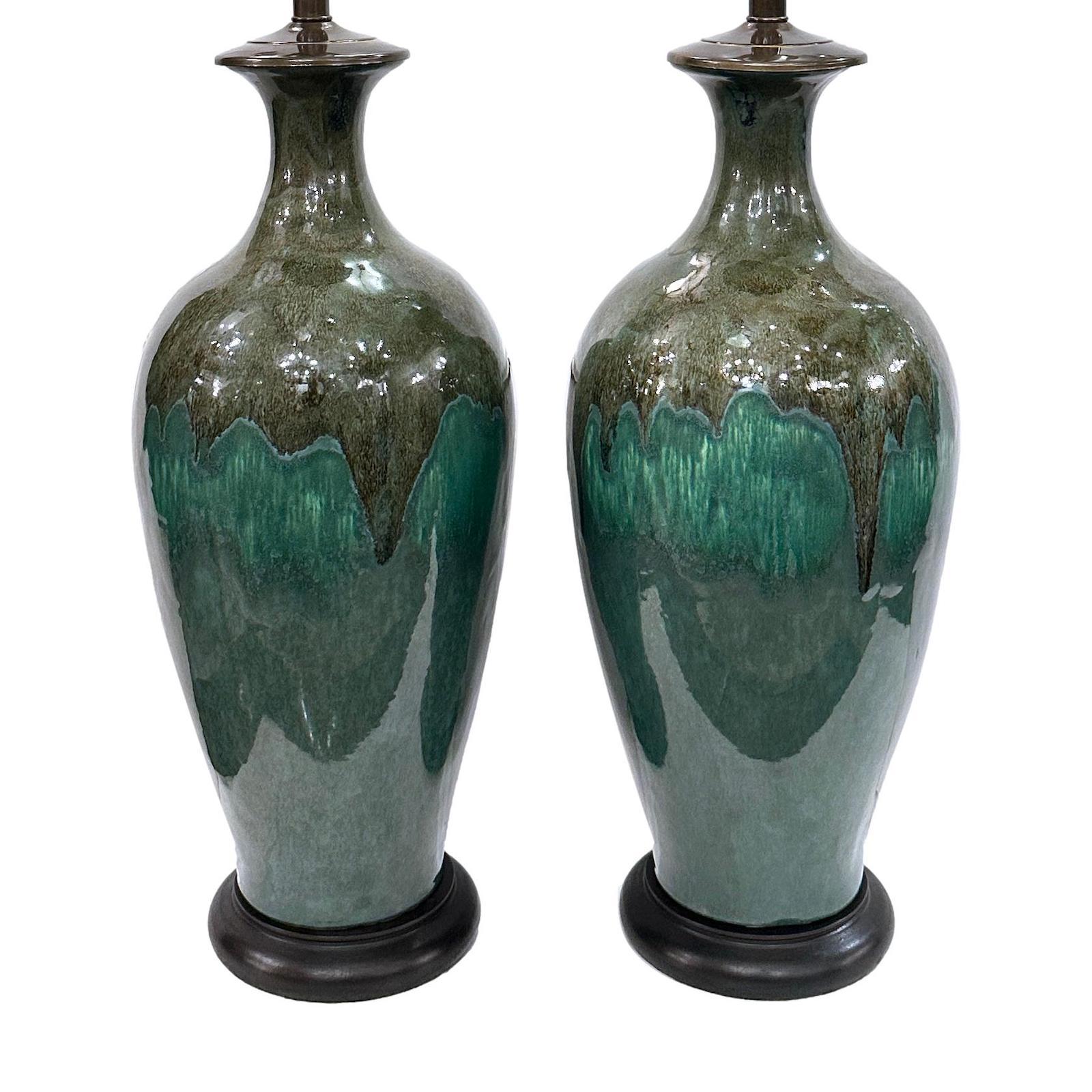 Pair of circa 1950's glazed porcelain lamps with wooden bases.

Measurements:
Height of body: 22.5
